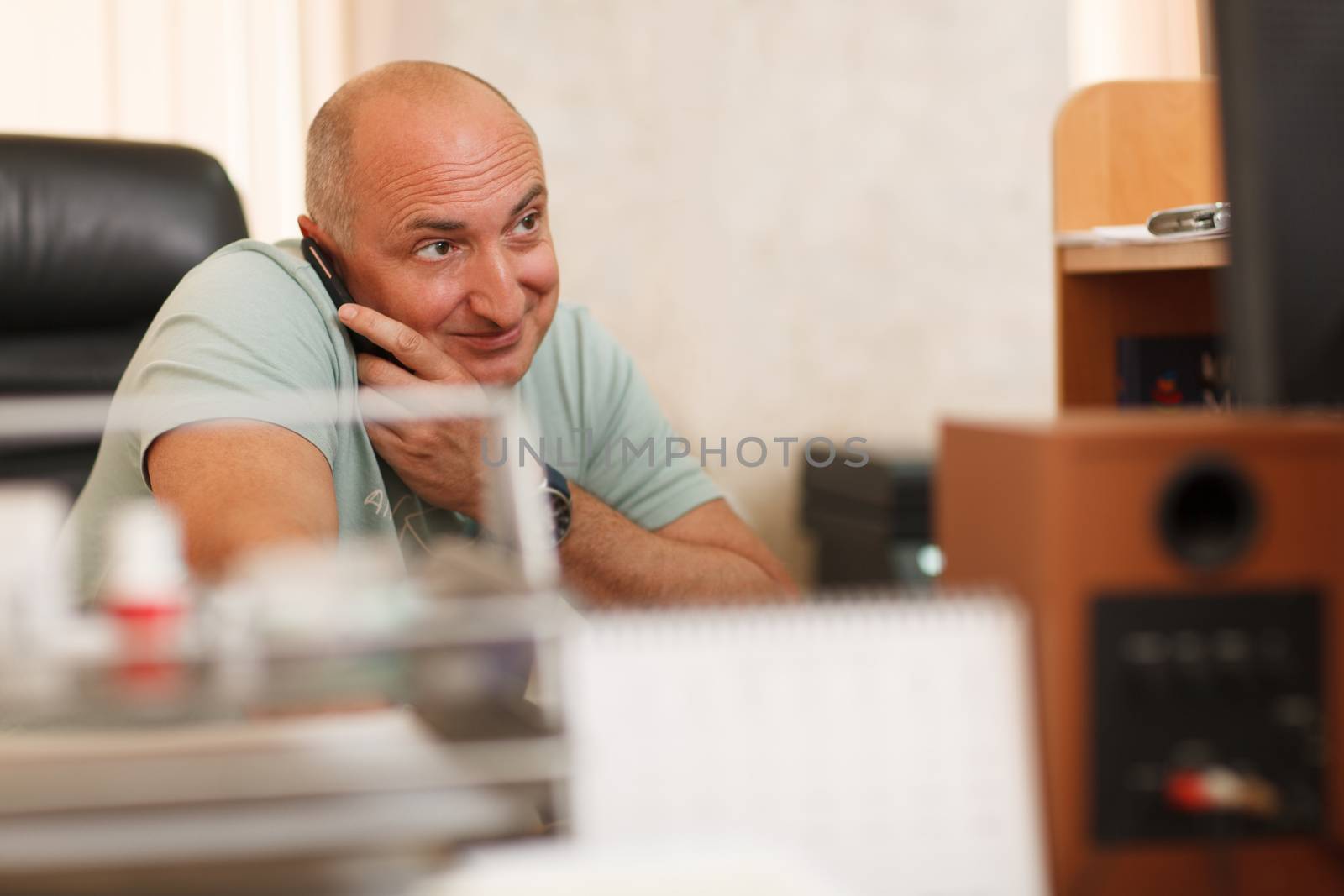 Middle-aged businessman on the phone while using his computer at the workplace