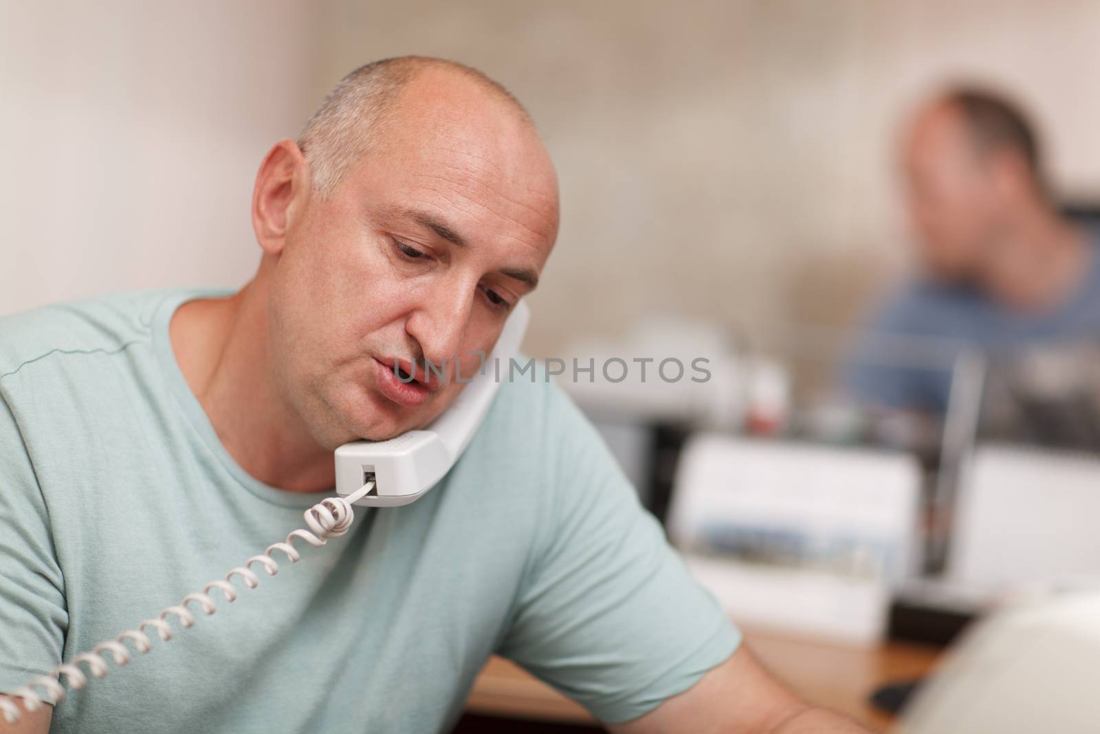 Middle-aged businessman  speaking on the phone and working in the office