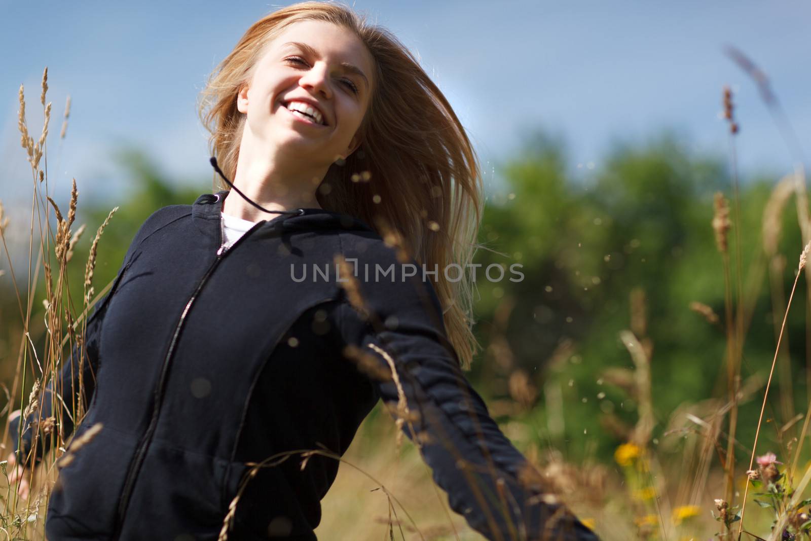Young happy girl of twenty running in the field and laughing