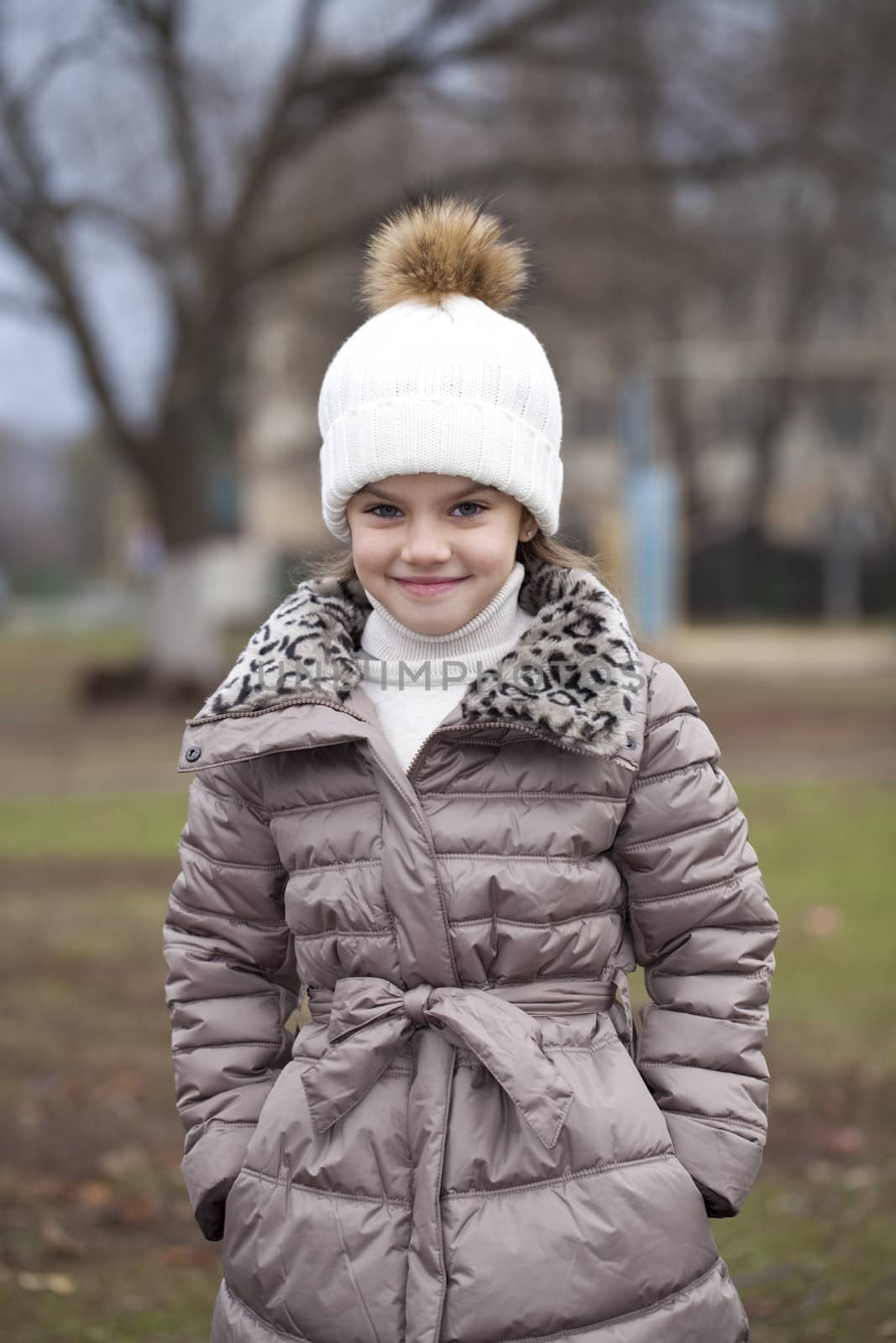 Portrait of beautiful little girl in a white knitted hat autumn