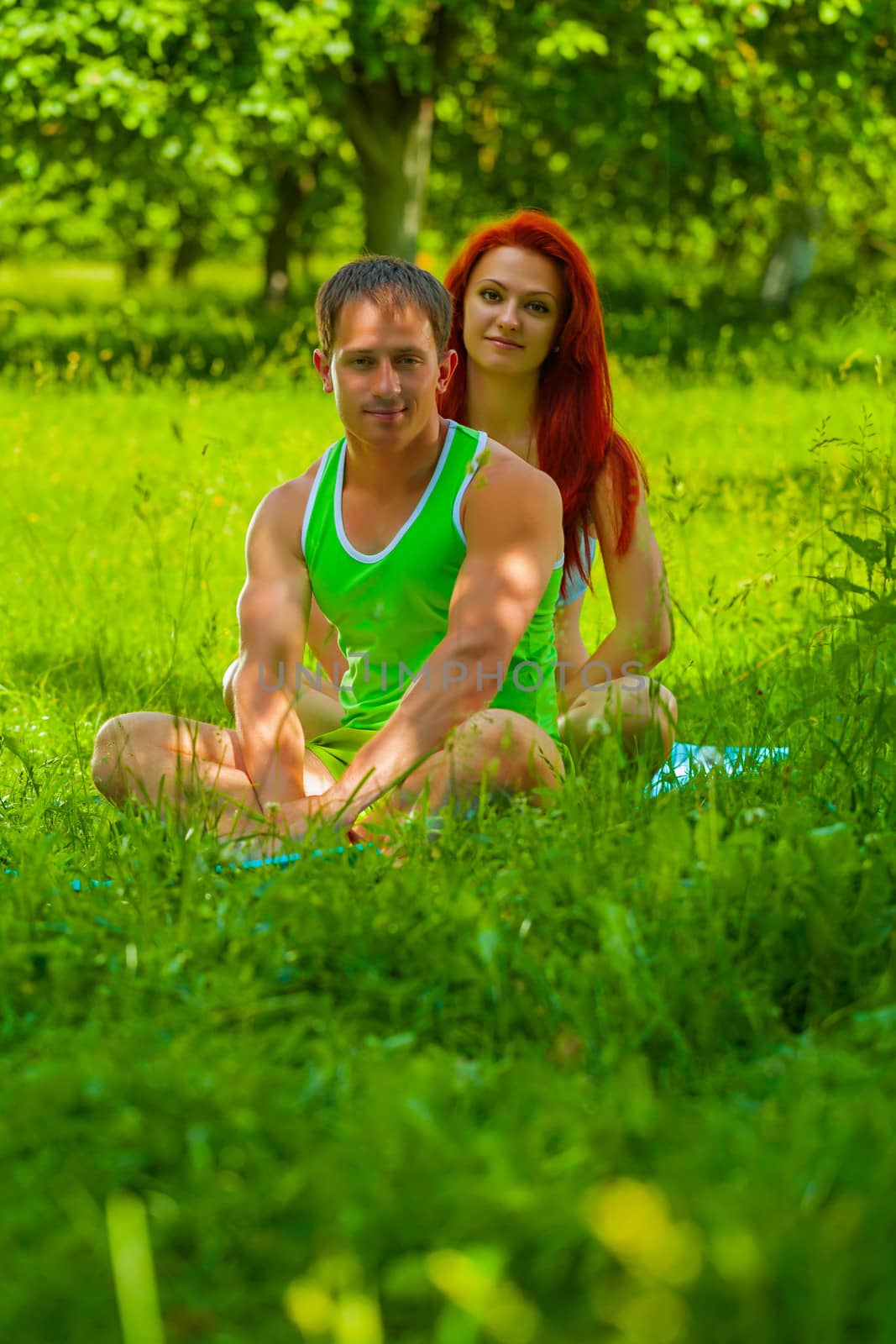 couple sitting on grass by mihalec