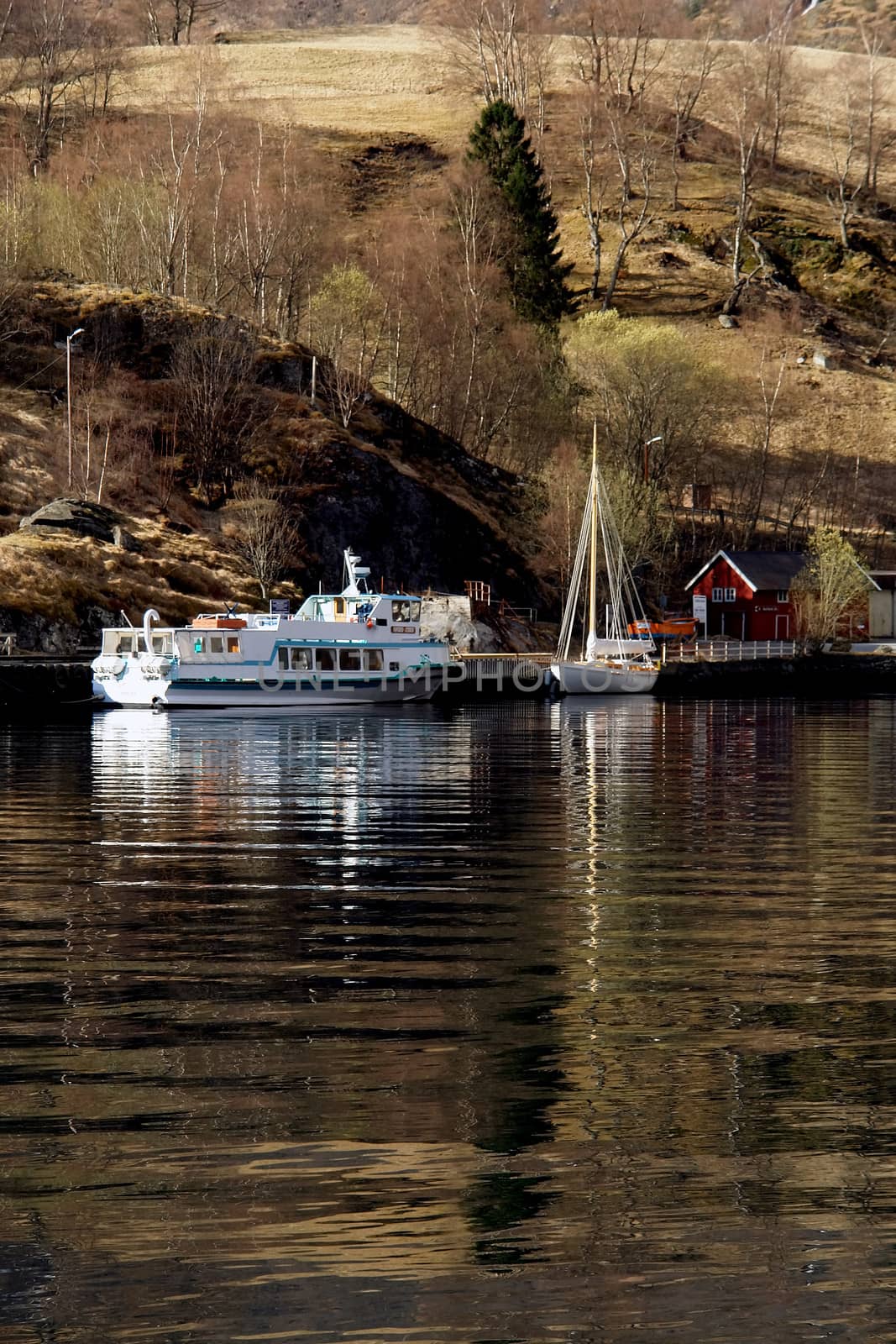 Boats in Flam port and reflex in fjord waters, Norway                               