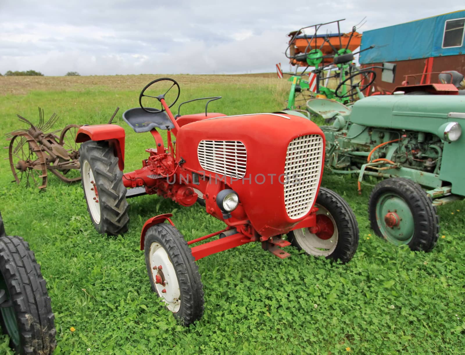 Close up of red antique tractor on green grass by cloudy day