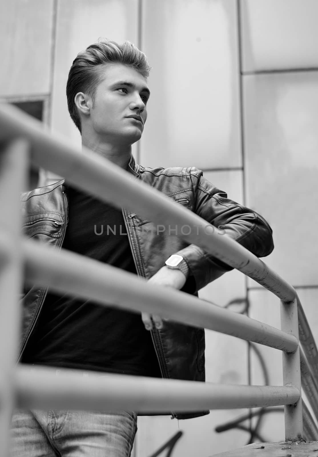 Handsome blond haired young man on metal railing, black and white shot