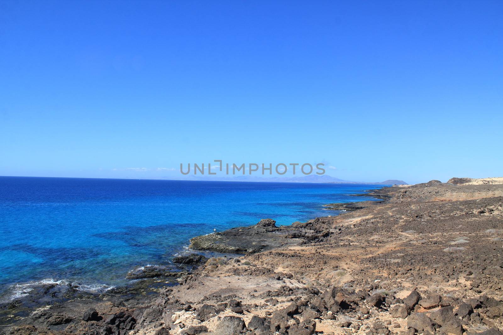 Turbulent ocean waves with white foam beat coastal stones, Fuerteventura, Canary Islands at La Pared