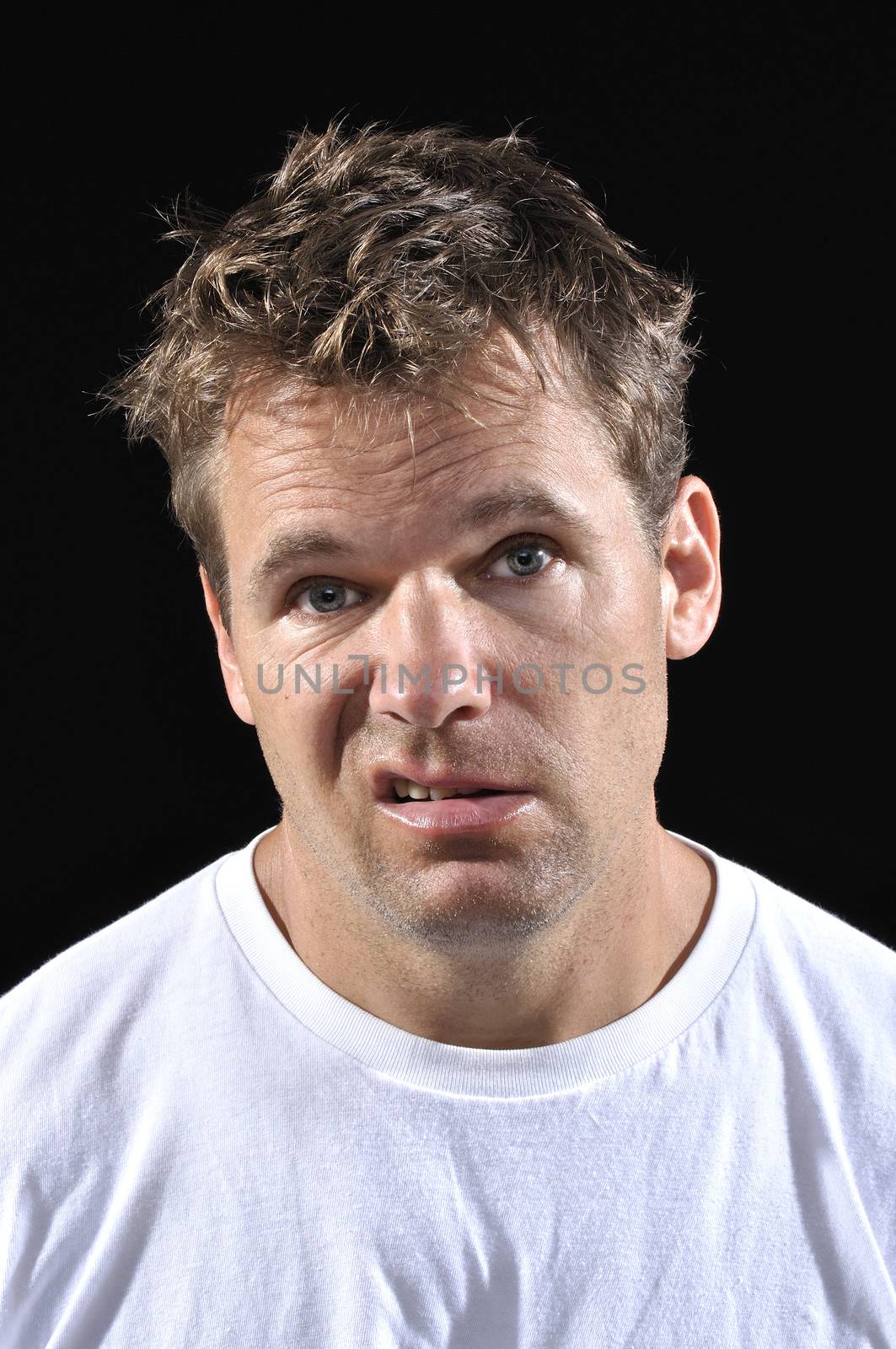 Mug shot of displeased crazy messy Caucasian man wearing a T-shirt on black background