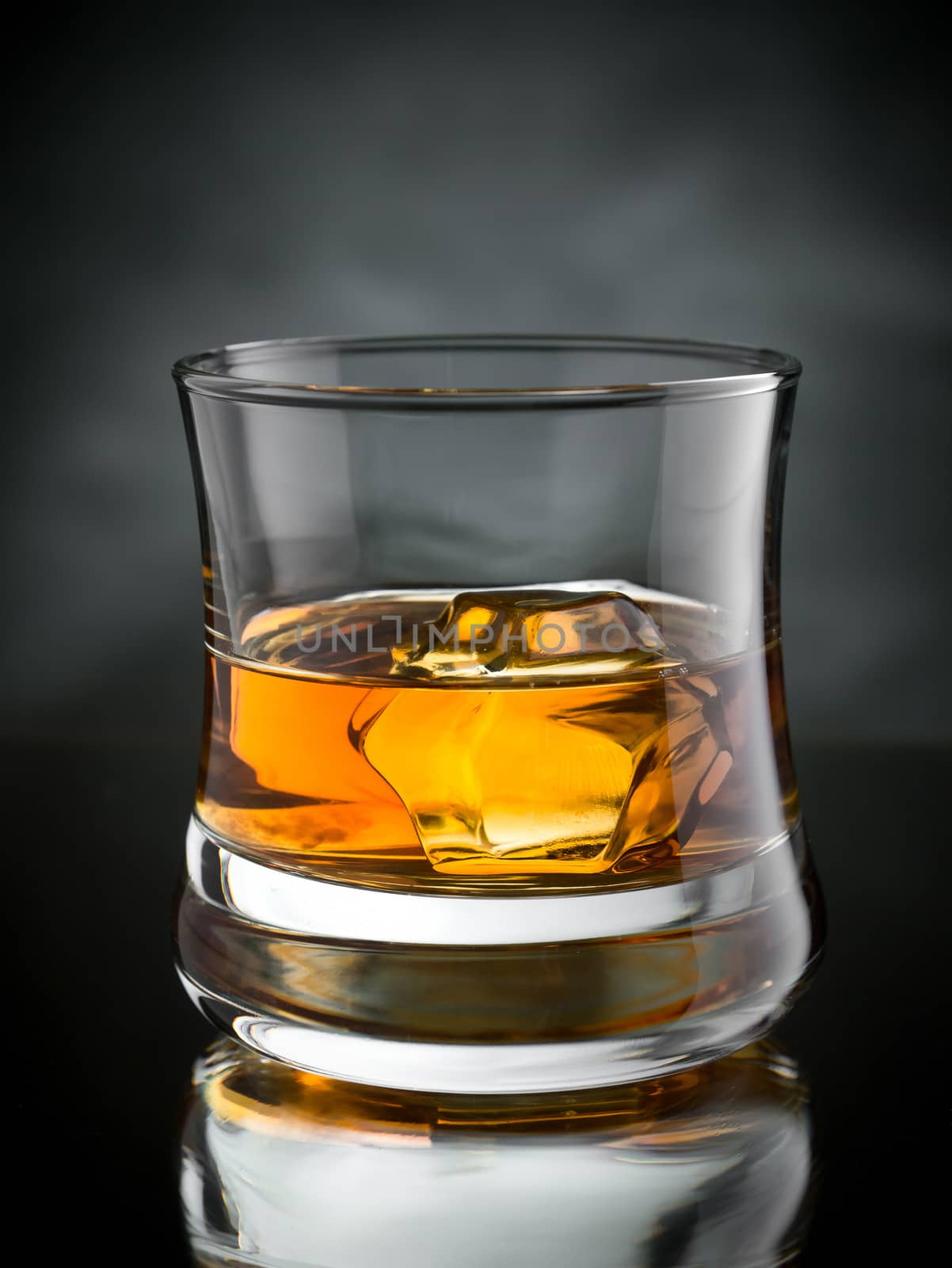 One glass of whisky on the rocks on black background