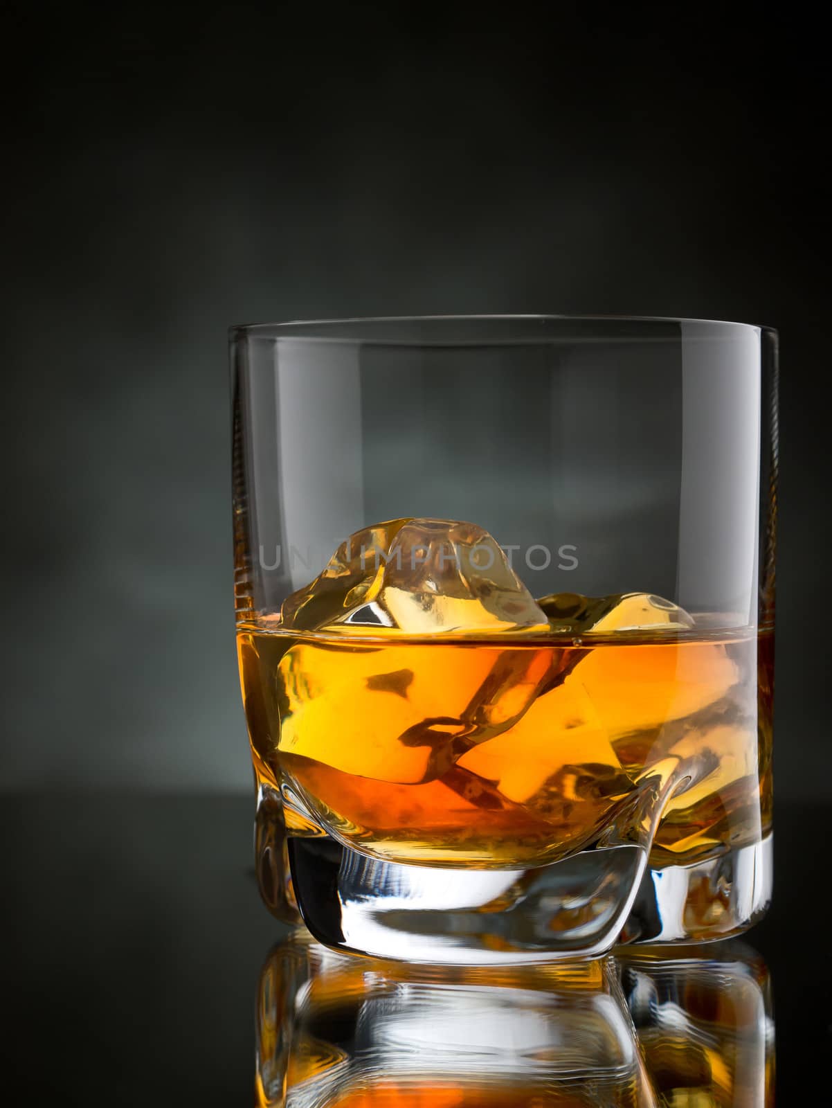 One glass of whisky on the rocks on black background