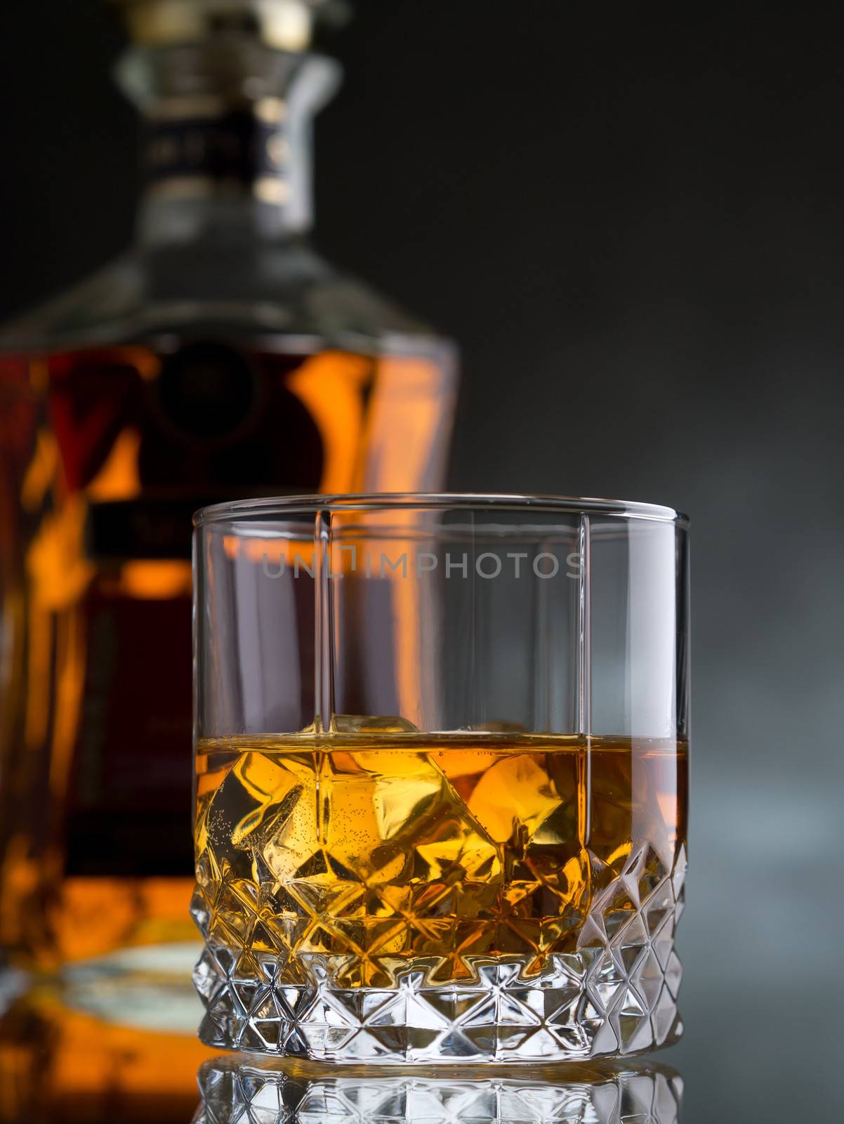 Glass of whisky on the rocks with a bottle