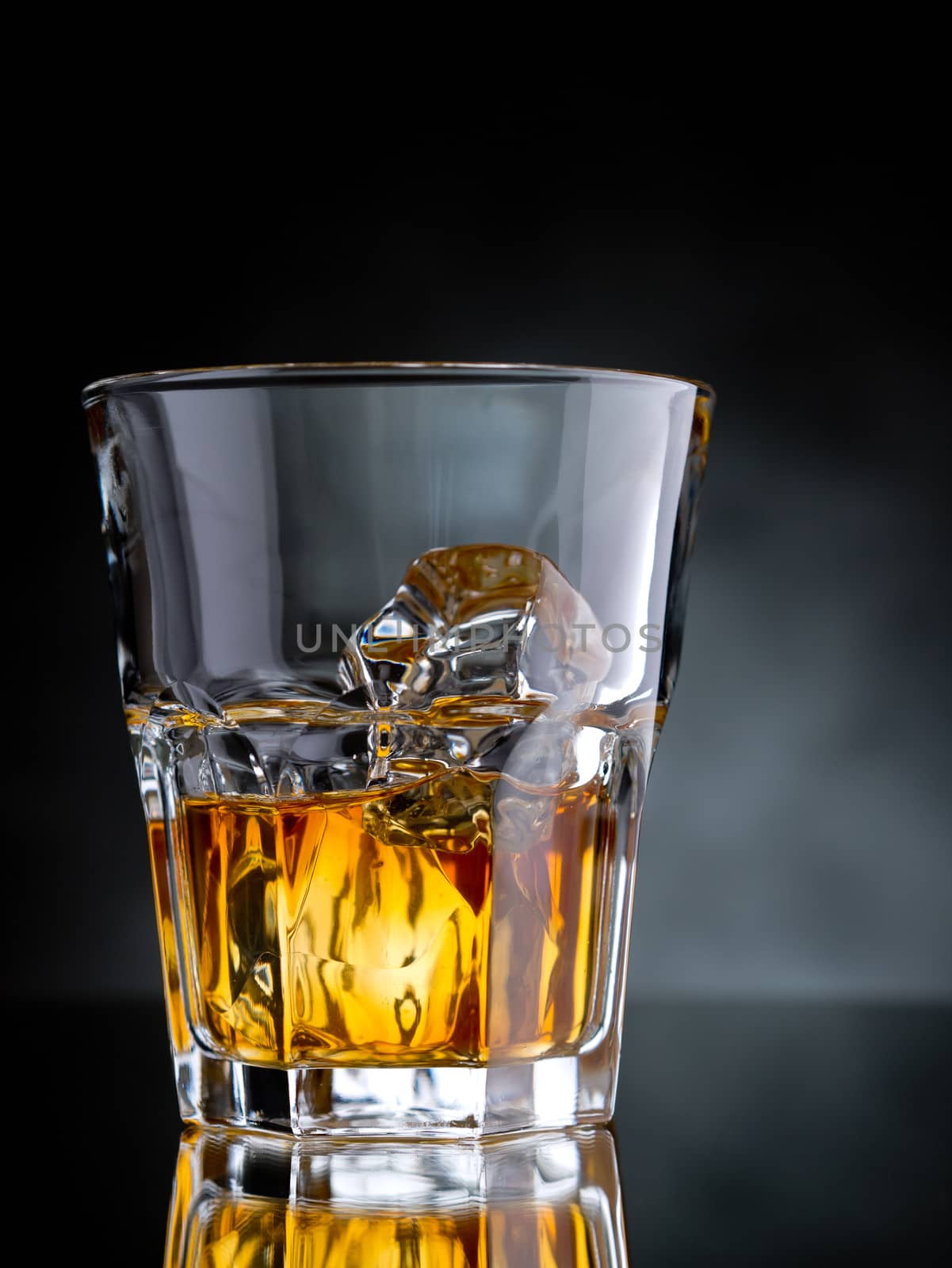 One glass of whisky on the rocks on black background