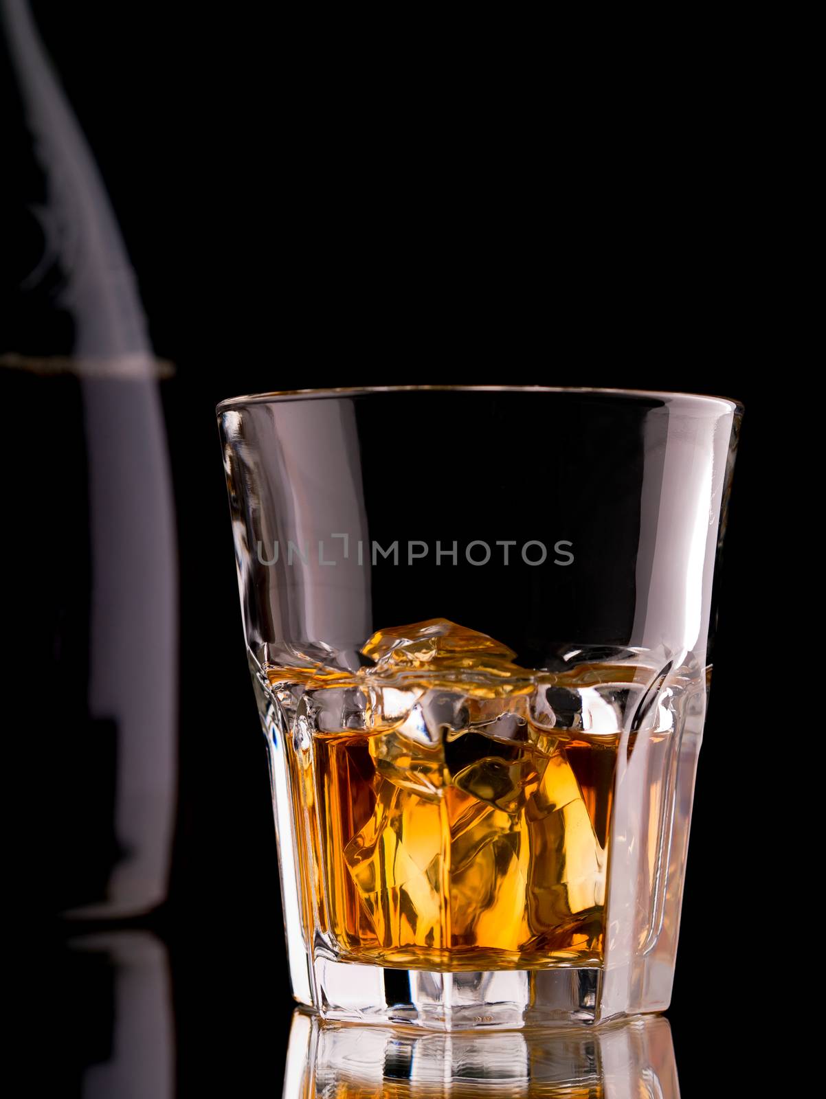 Glass of whisky on the rocks with a bottle
