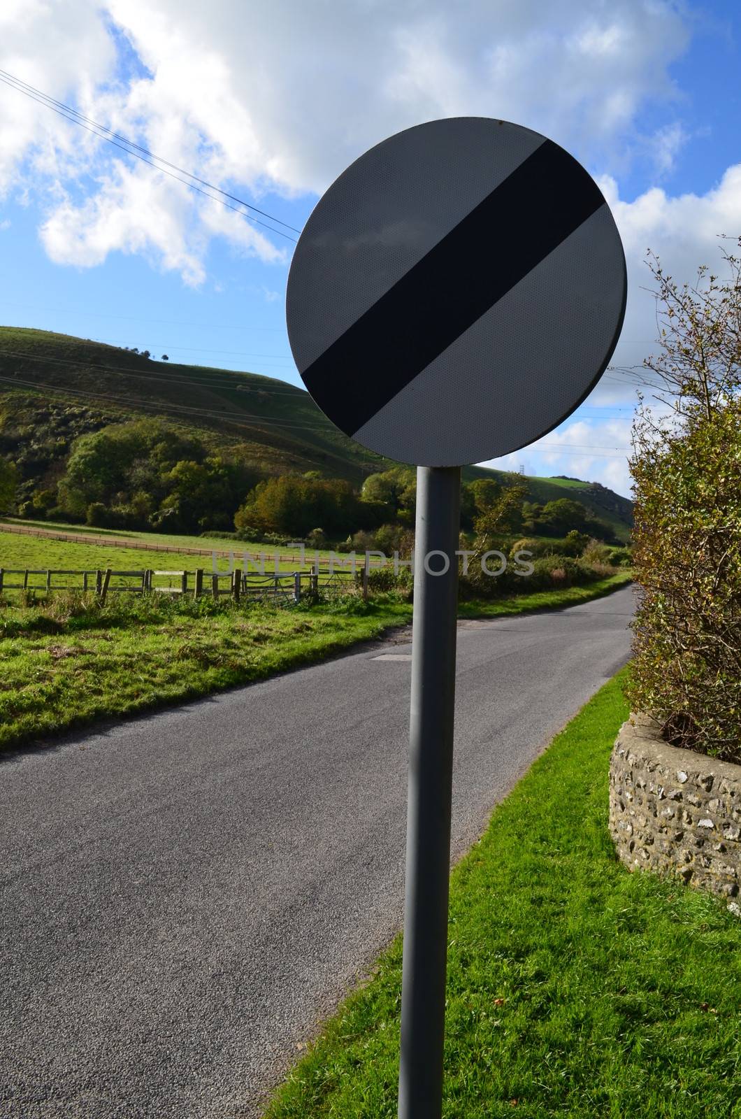 British national speed limit traffic road sign on a rural road in Southern England.