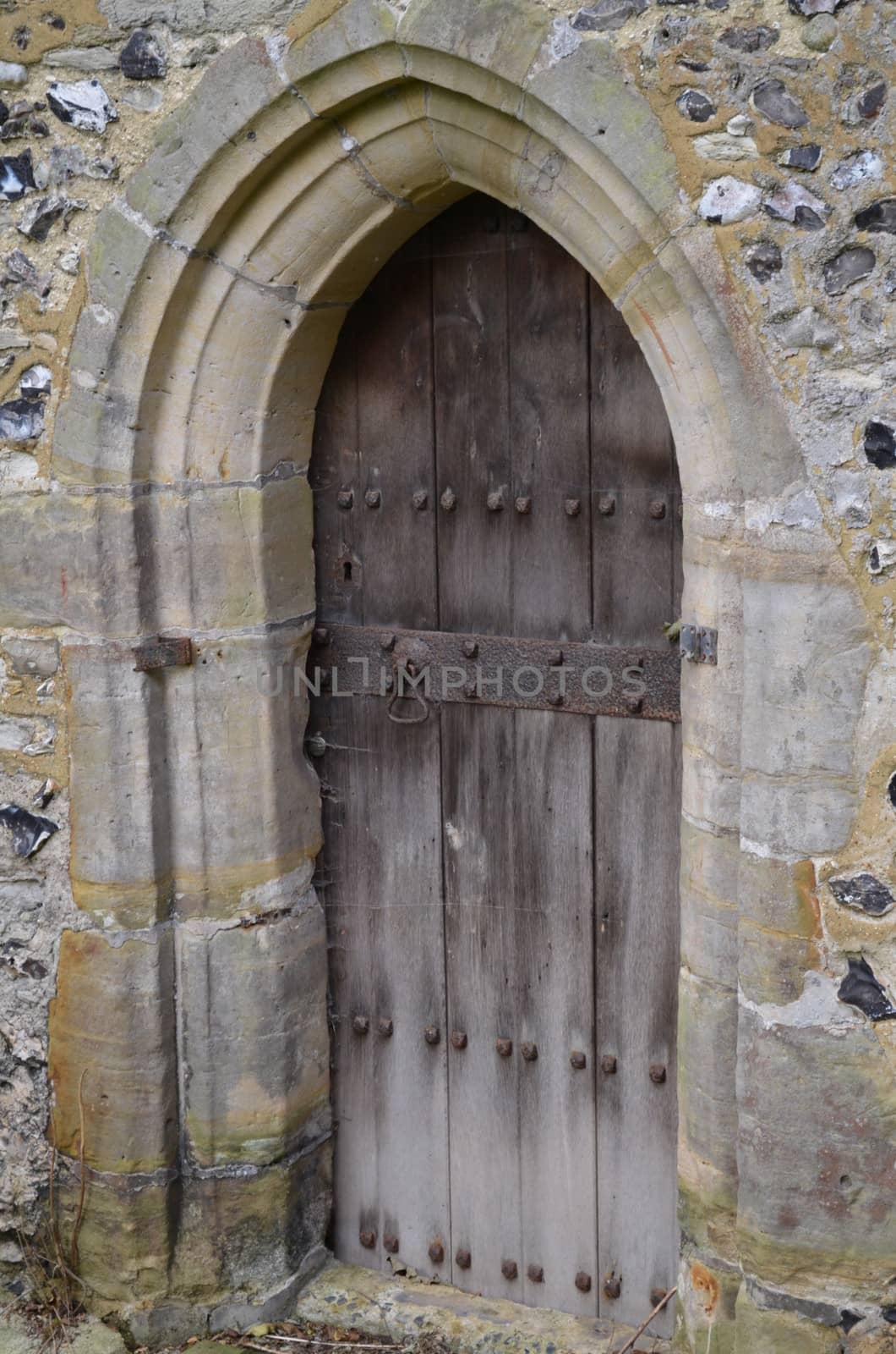 Ancient church doorway with solid oak wood door with stone frame and arch.Shot taken at St Andrews a 12th century late Norman style church at Edburton,Sussex,England.