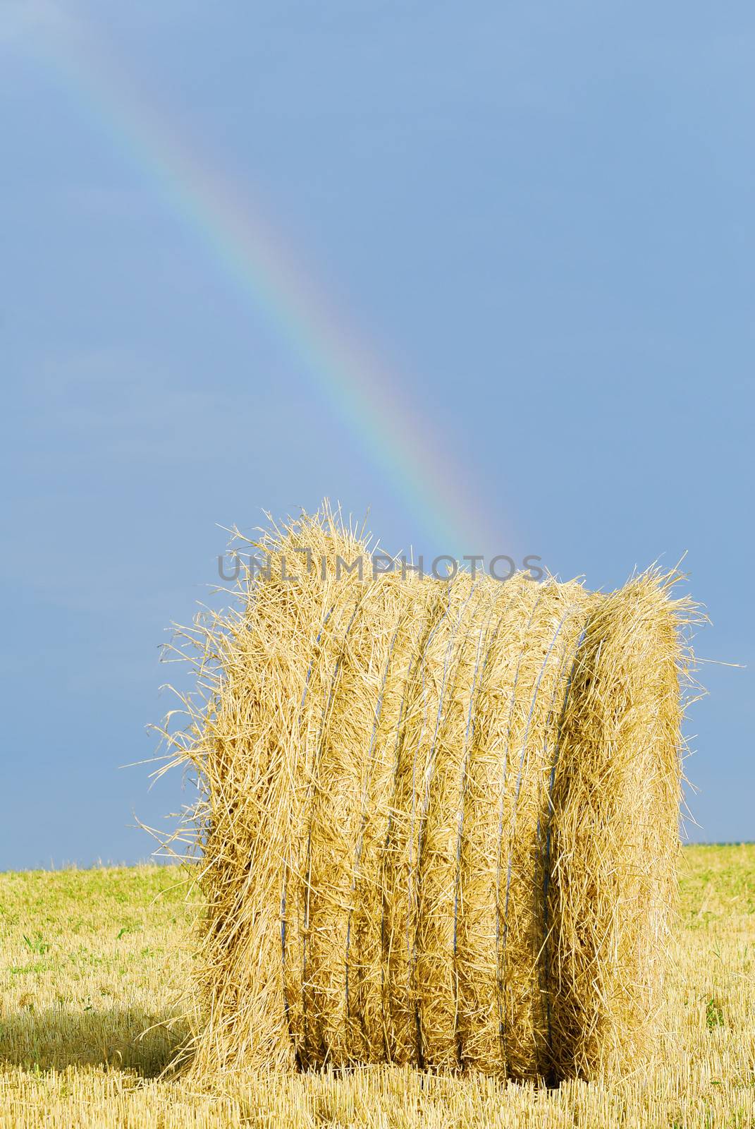 straw bale under stormy sky and rainbow