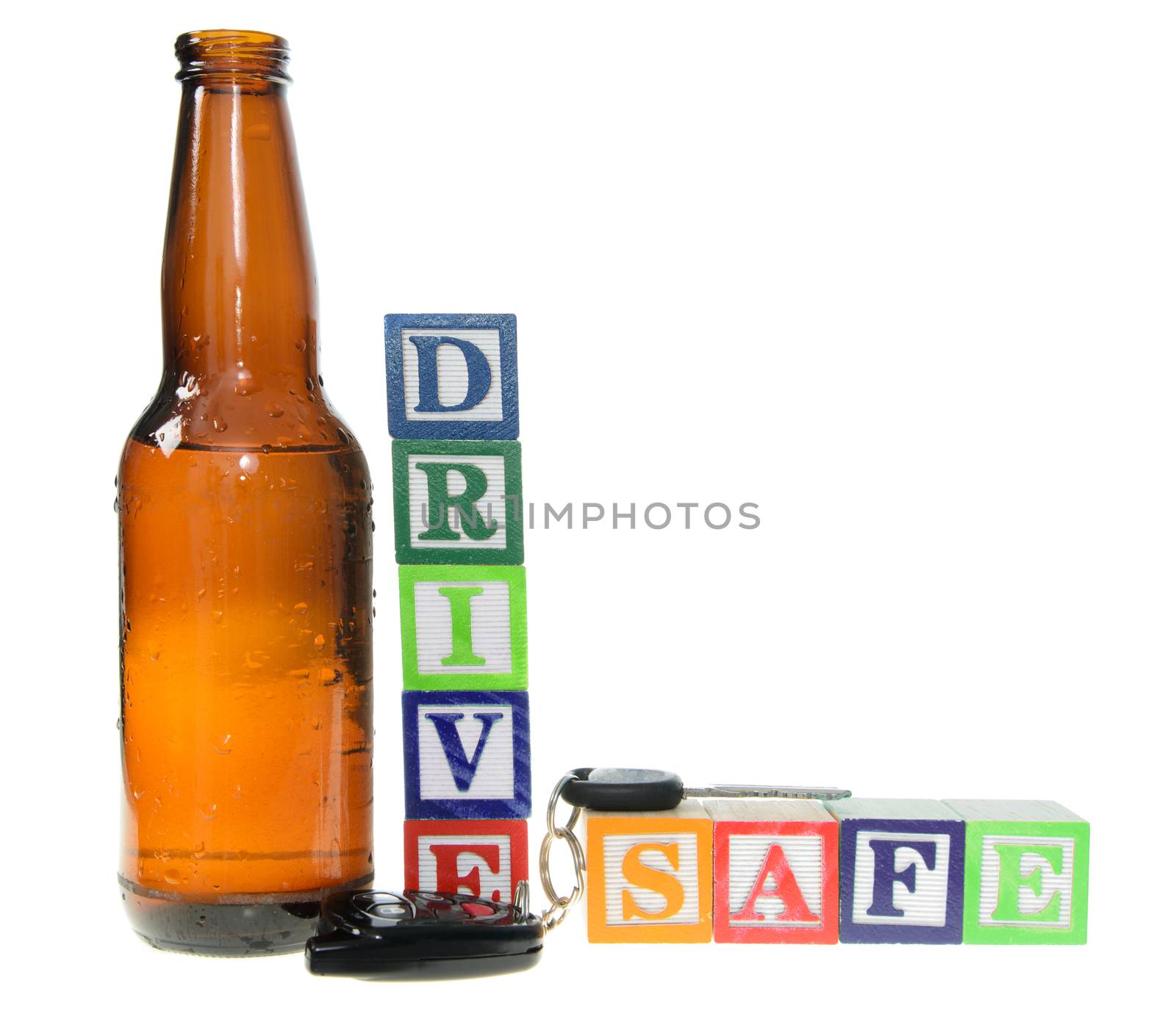 Letter blocks spelling drive safe with a beer bottle and keys. Isolated on a white background