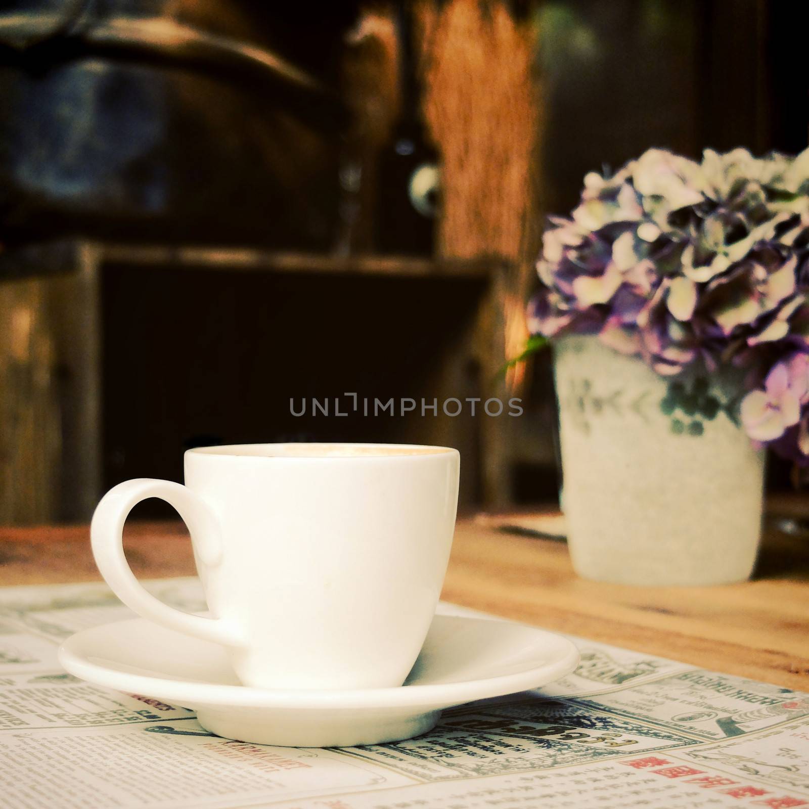 Cup of coffee with newspaper at coffee shop, retro filter effect