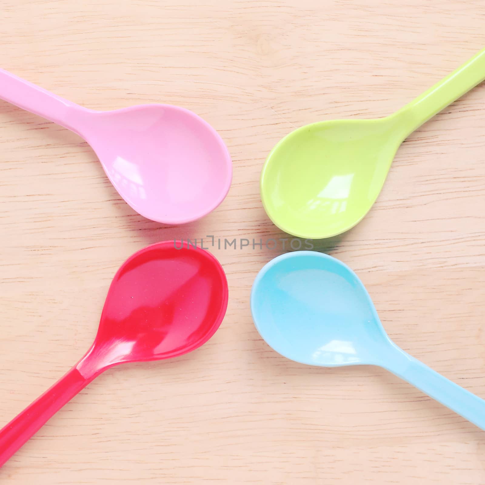 Colorful plastic spoons on wood with retro filter effect