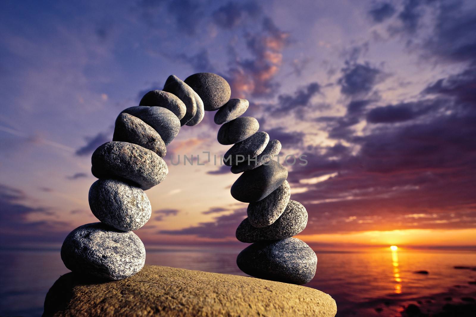 Balancing of pebbles on the boulder in the evening