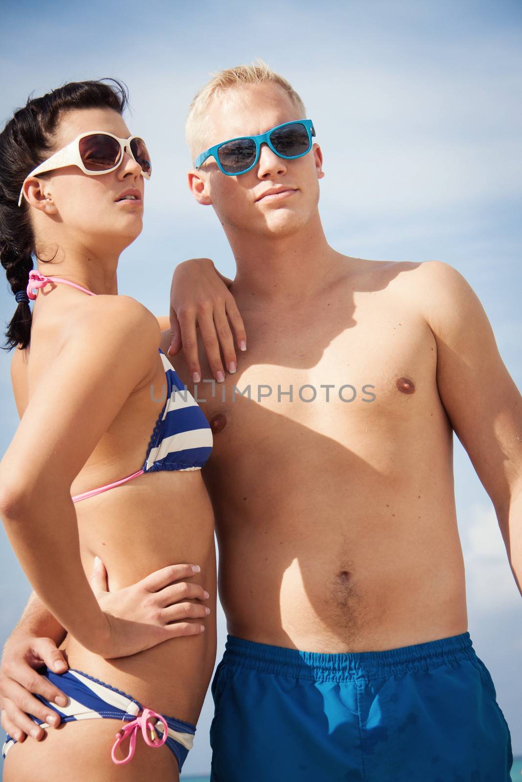 attractive young couple in swimwear and sunglasses on the beach 