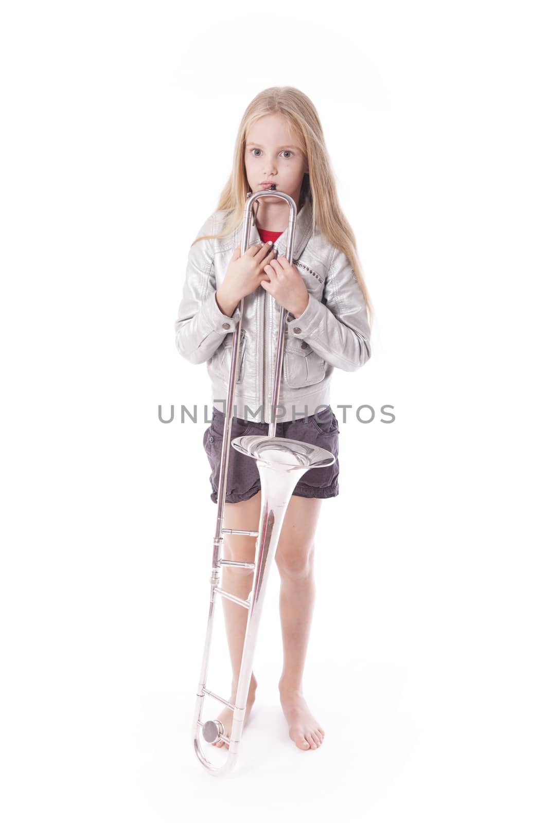 young girl in silver jacket standing with her trombone in studio against white background