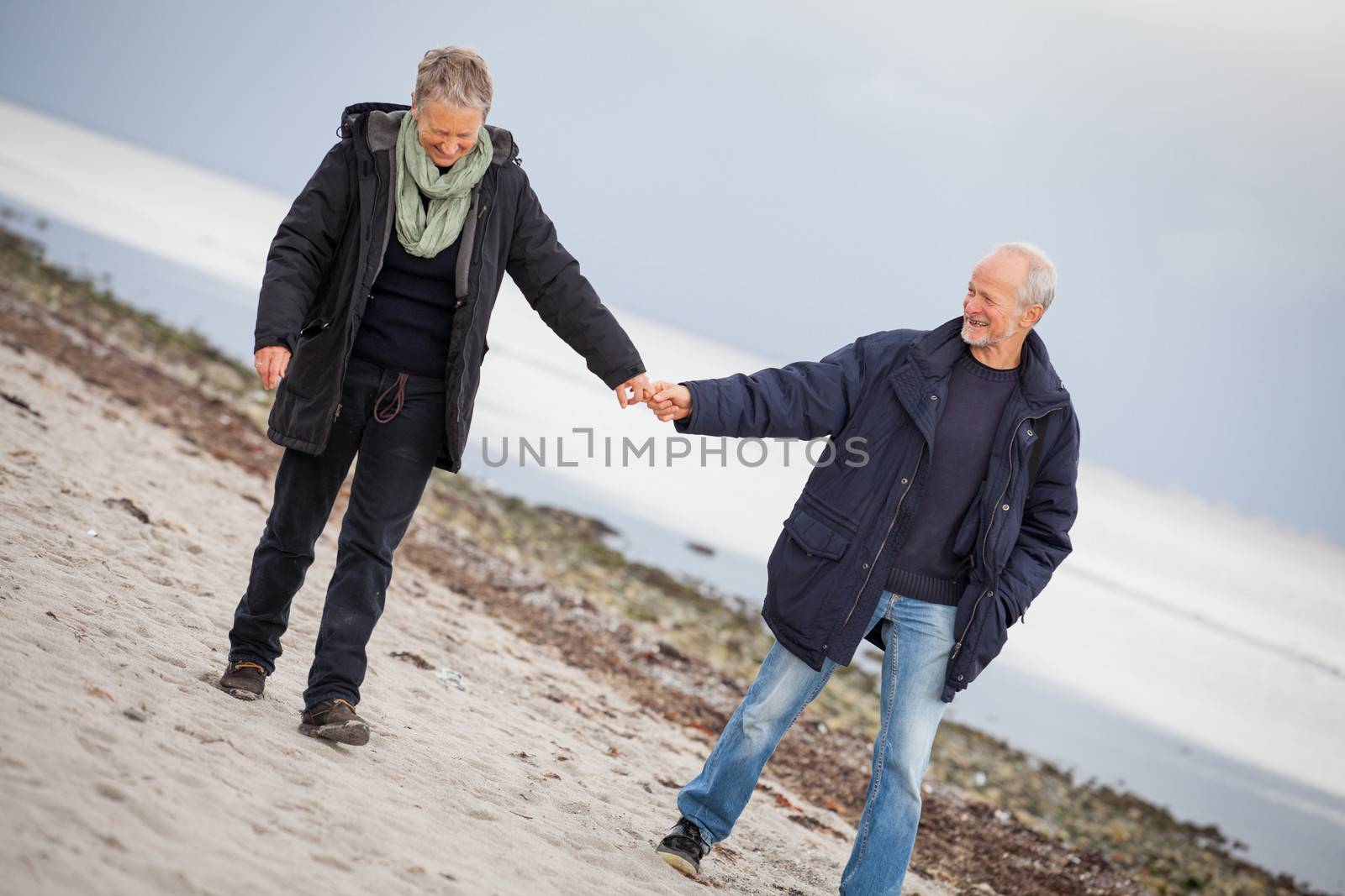 mature happy couple walking on beach in autumn lifestyle healthy