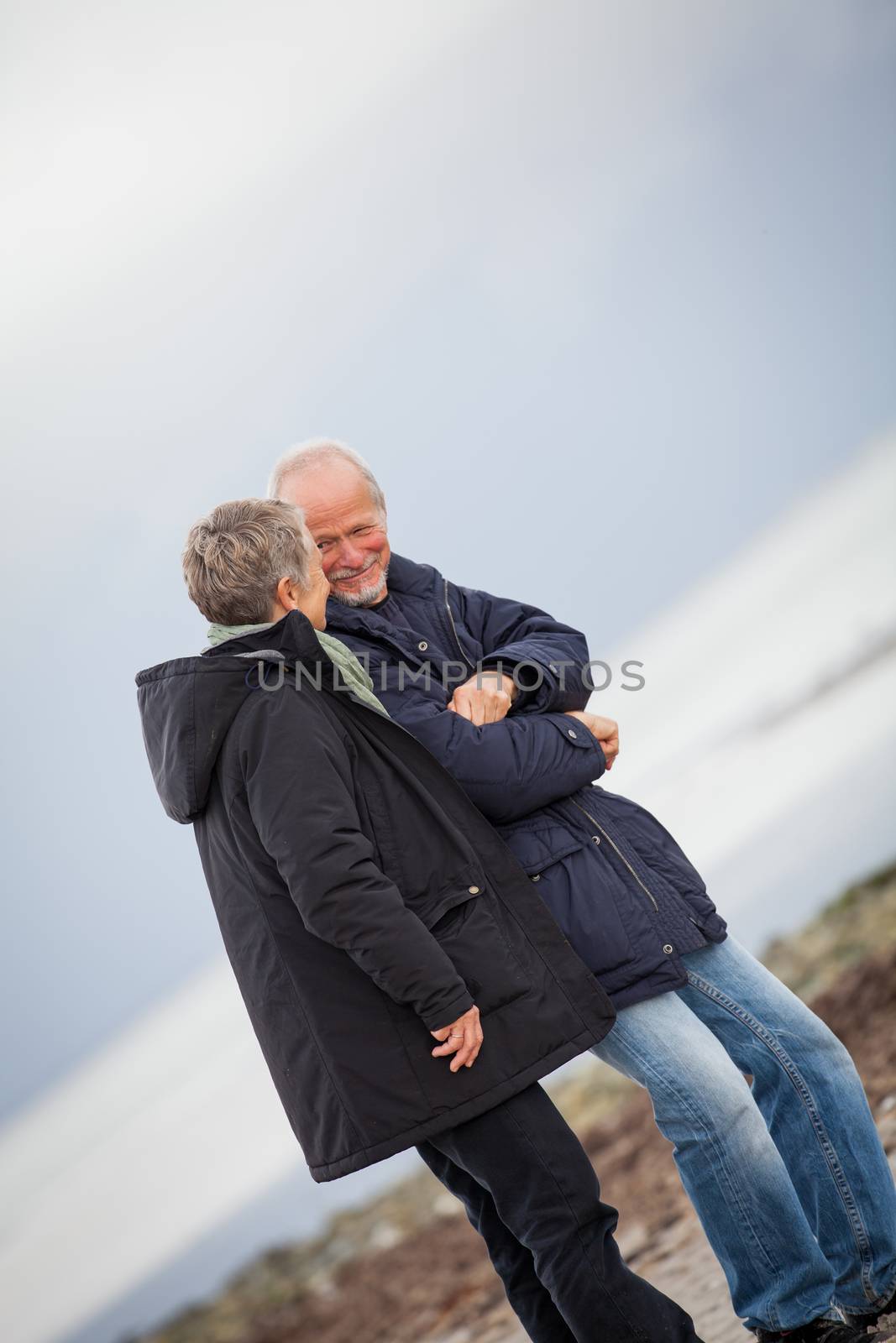 mature happy couple walking on beach in autumn by juniart