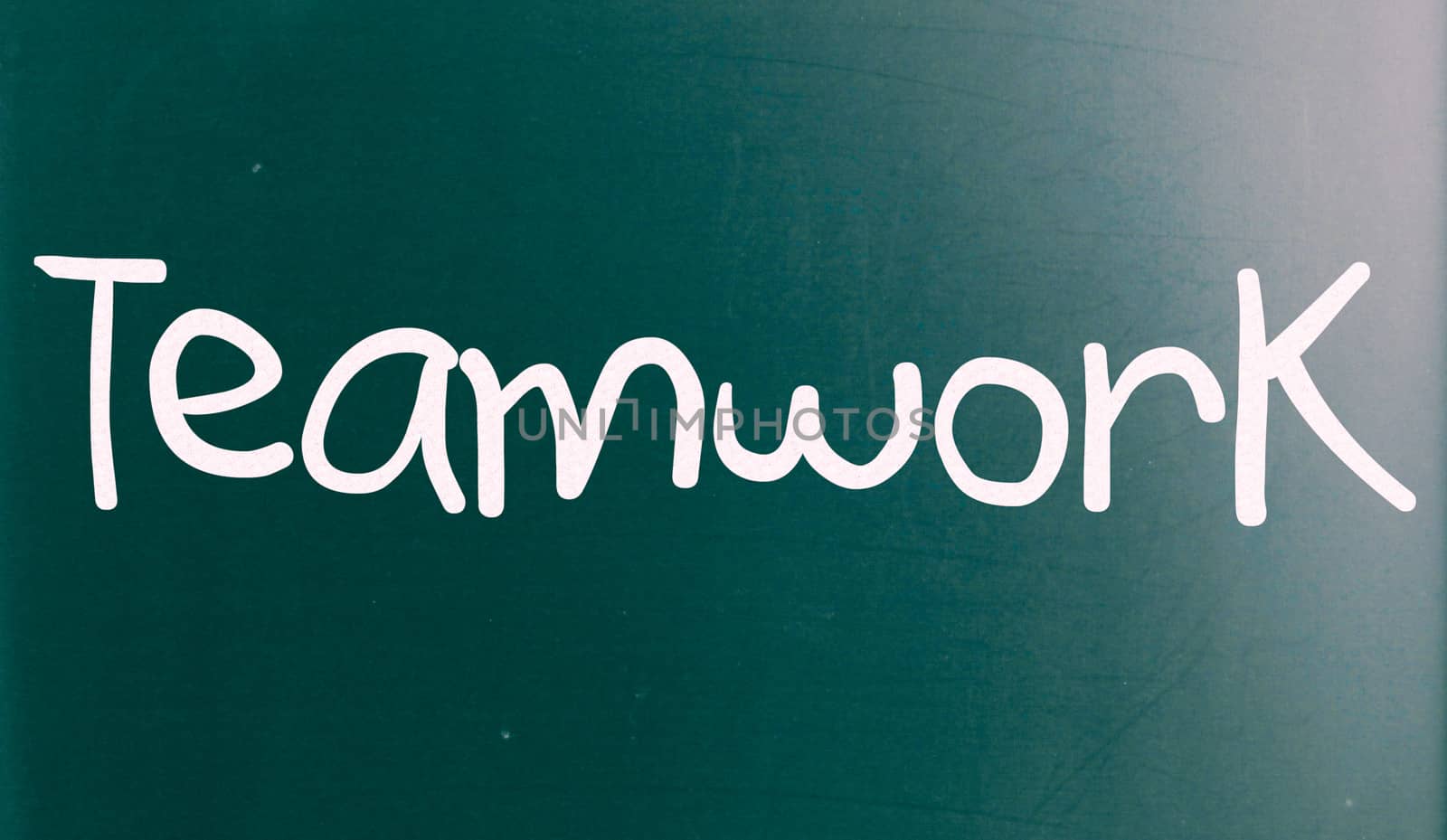 The word "Teamwork" handwritten with white chalk on a blackboard