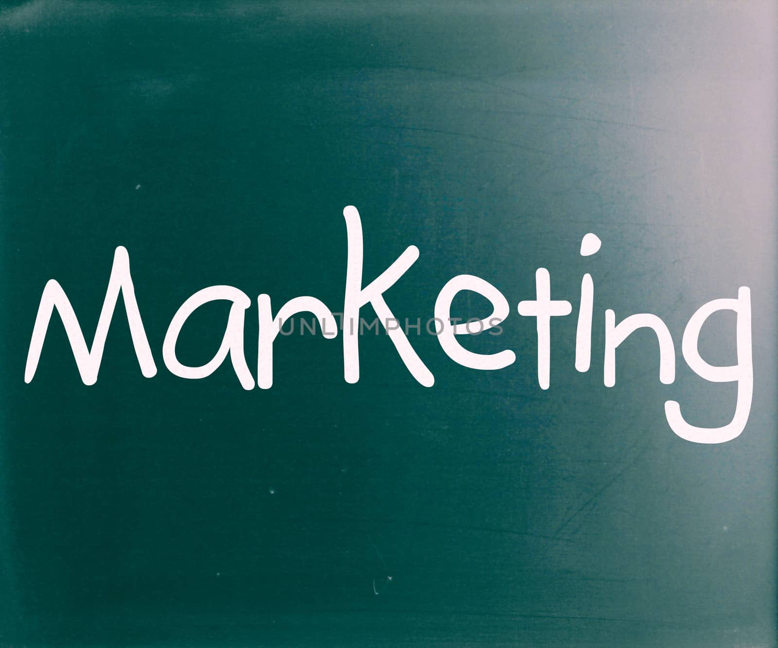 The word "Marketing" handwritten with white chalk on a blackboar by nenov