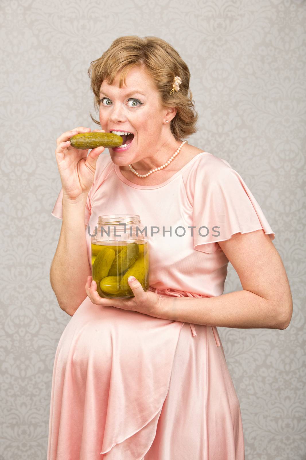 Happy pregnant person eating from a jar of pickles
