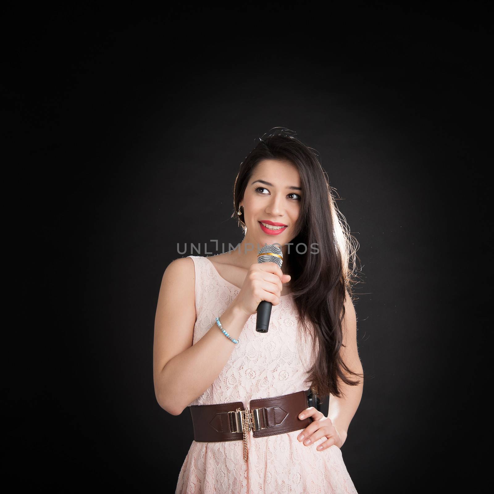 beautiful singer on a black background with a microphone