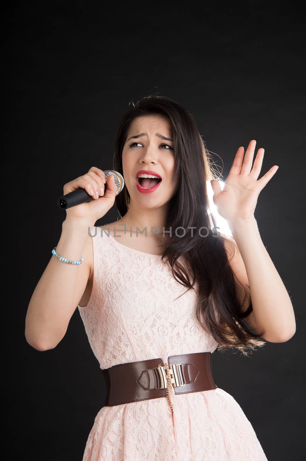 beautiful singer on a black background with a microphone