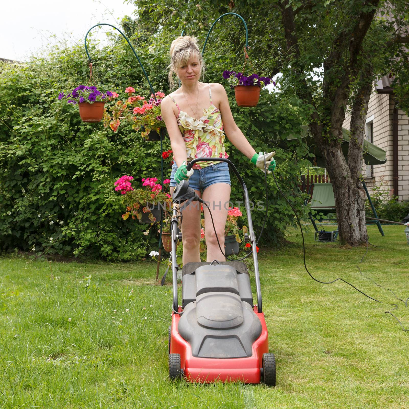 Woman mowed grass in a flower garden