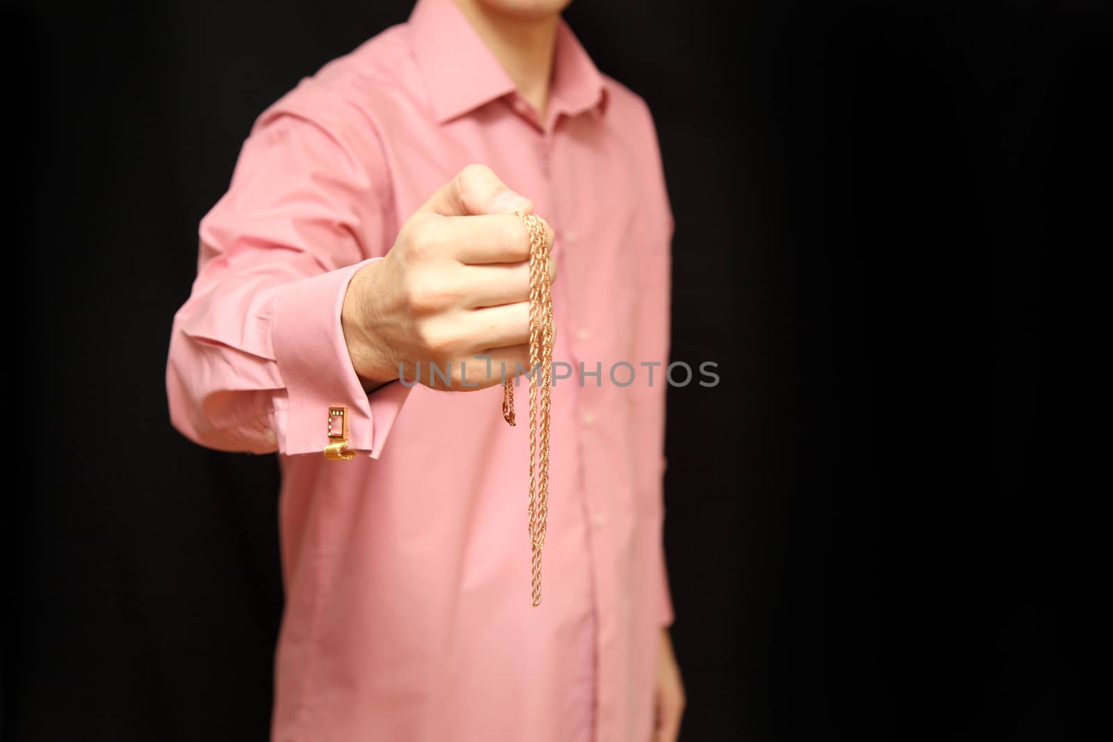 man holds in hand a gold chain