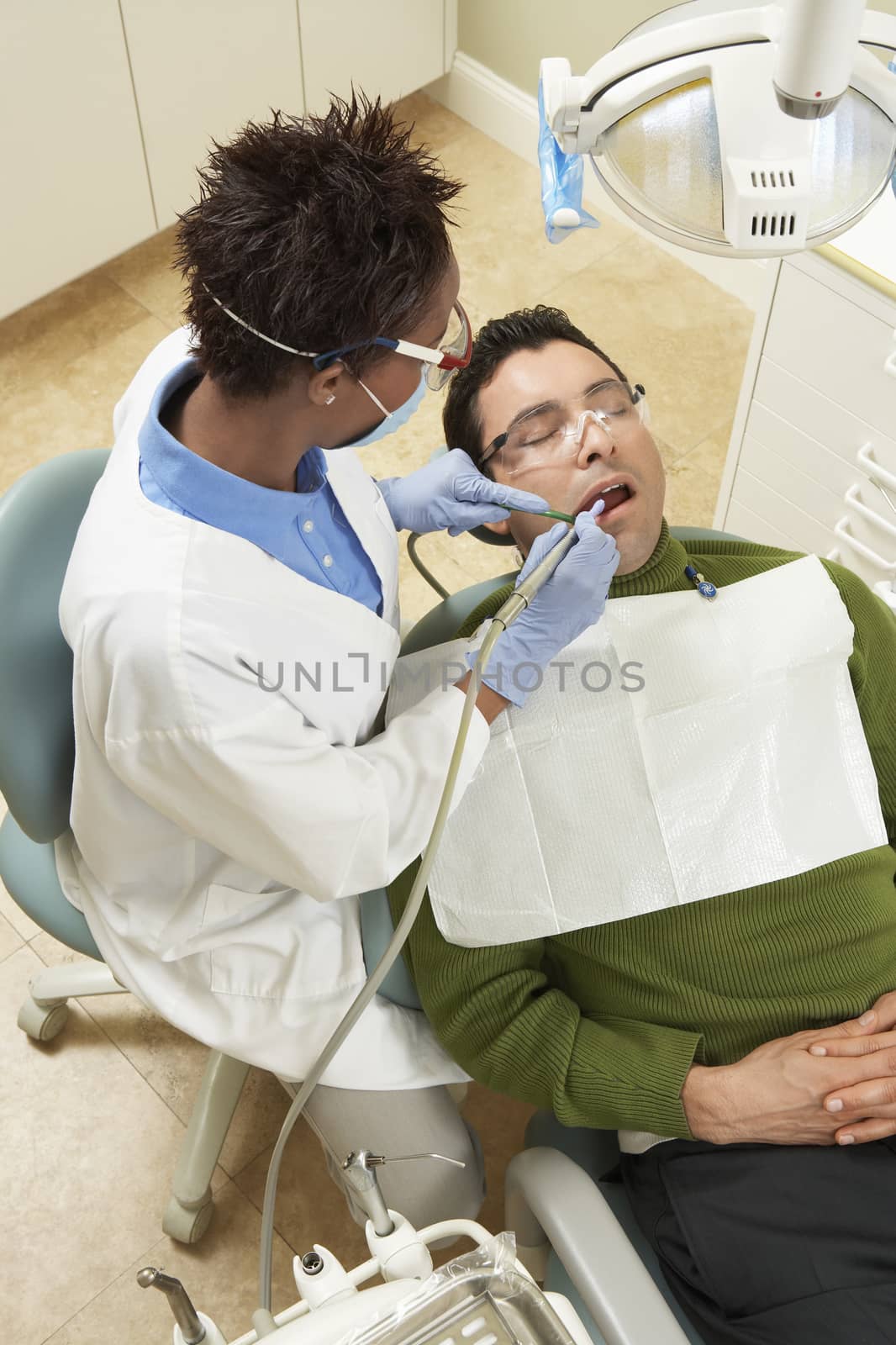 High angle view of female dentist treating male patient at clinic by moodboard
