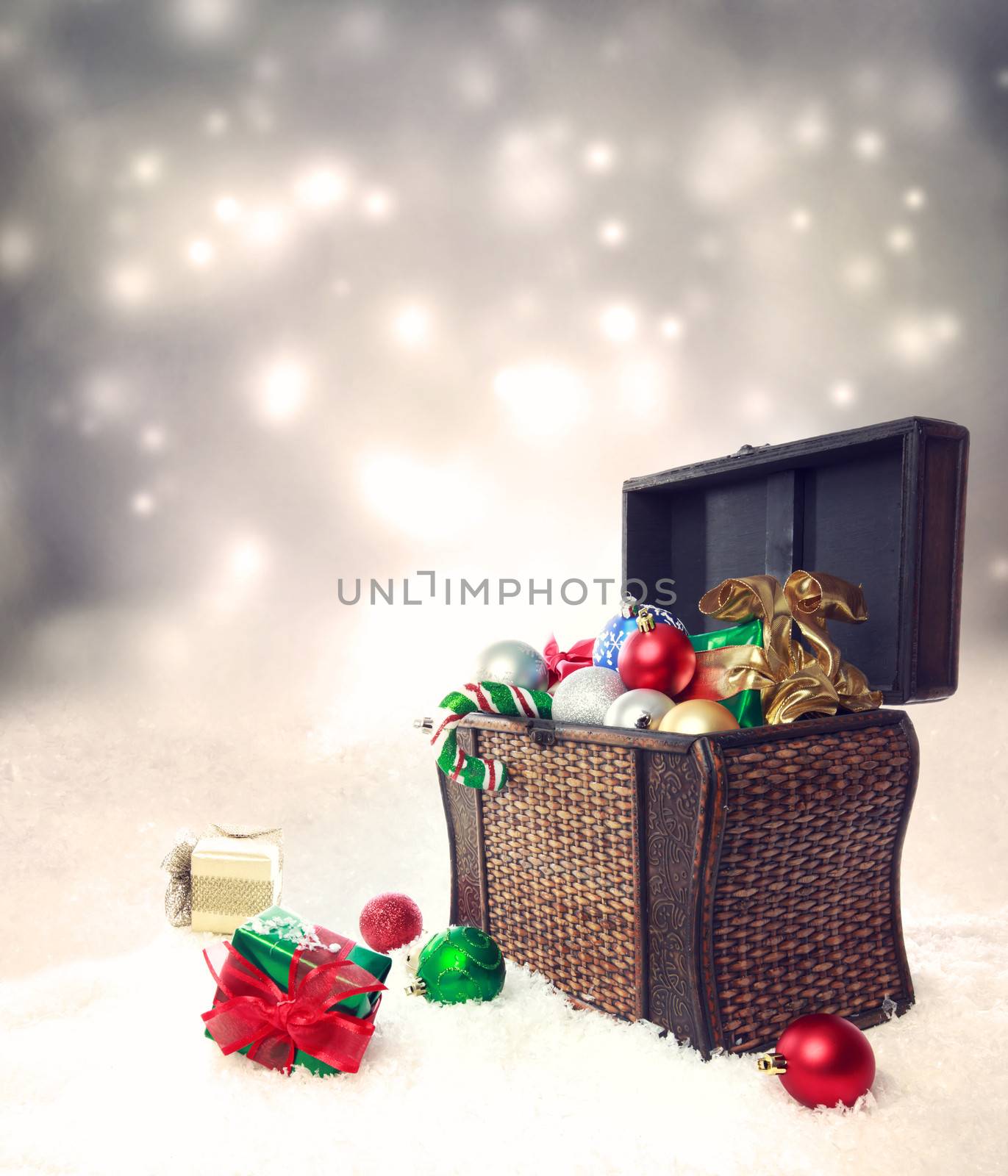 Treasure box filled with Christmas ornaments and presents on snow