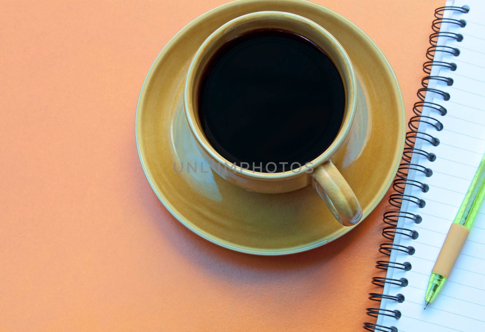 Coffee cup and pen on a red background.