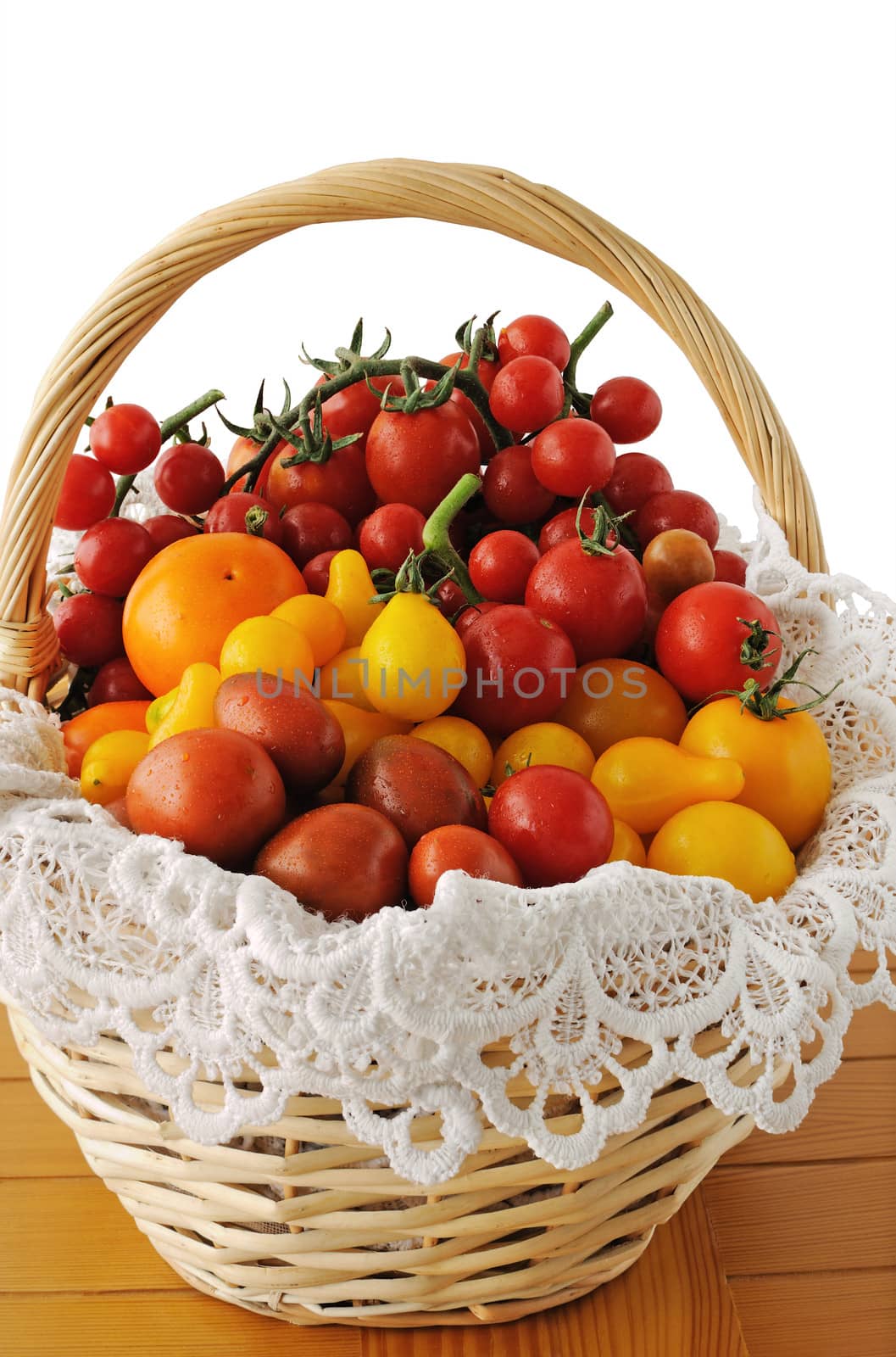 Different varieties of tomatoes in a basket on a wooden table