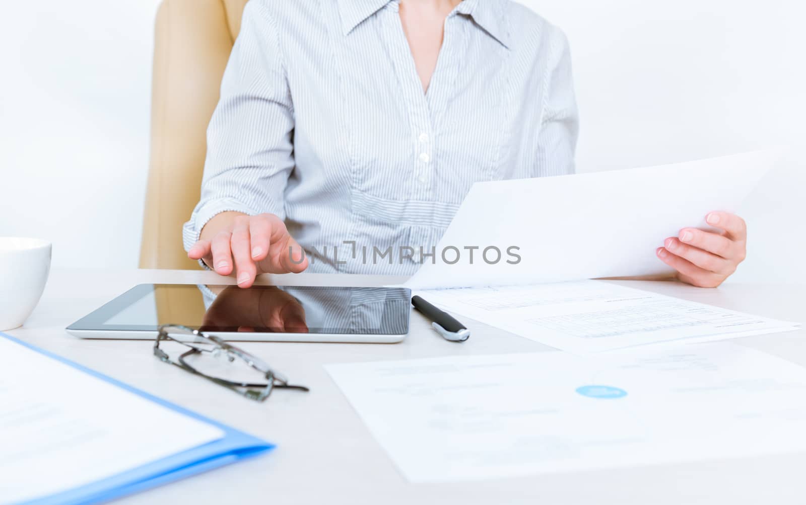 Business person wearing in casual shirt sitting at desk and check documents with the help of digital tablet in the office