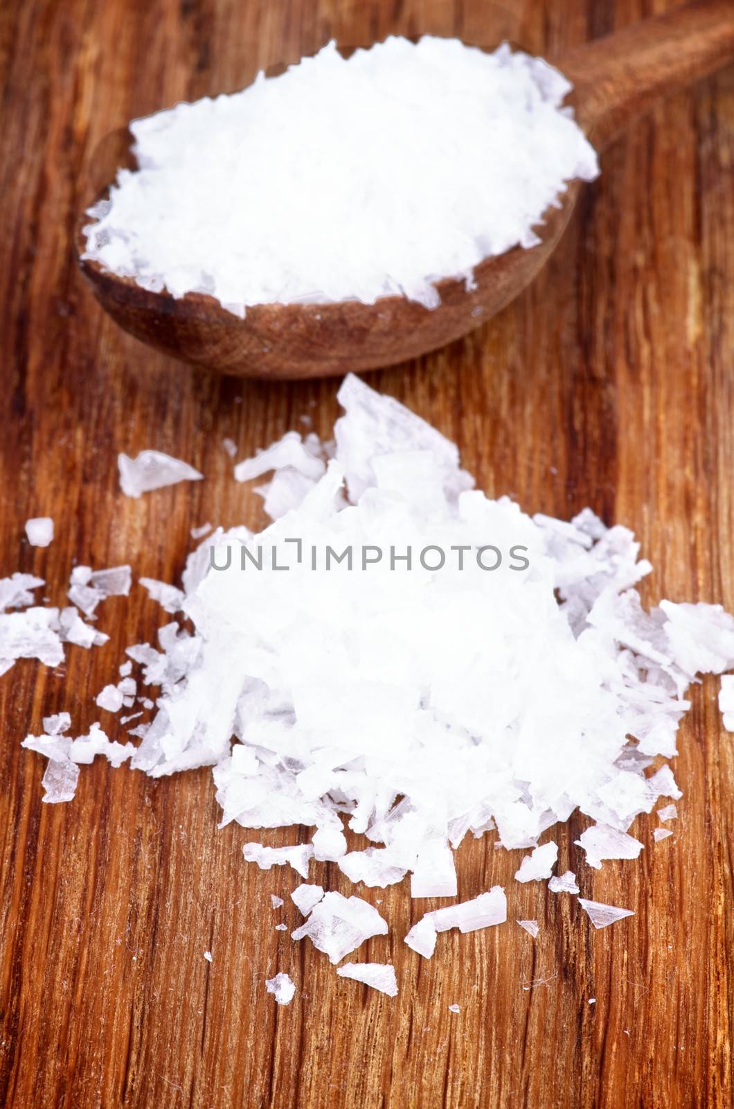 Heap and Wooden Spoon of White Crystal Salt on Wooden background 