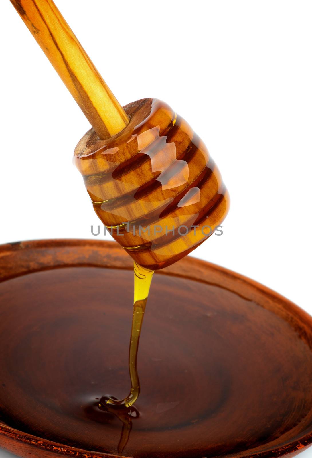 Honey Dripped from Wooden Dipper into Brown Plate closeup