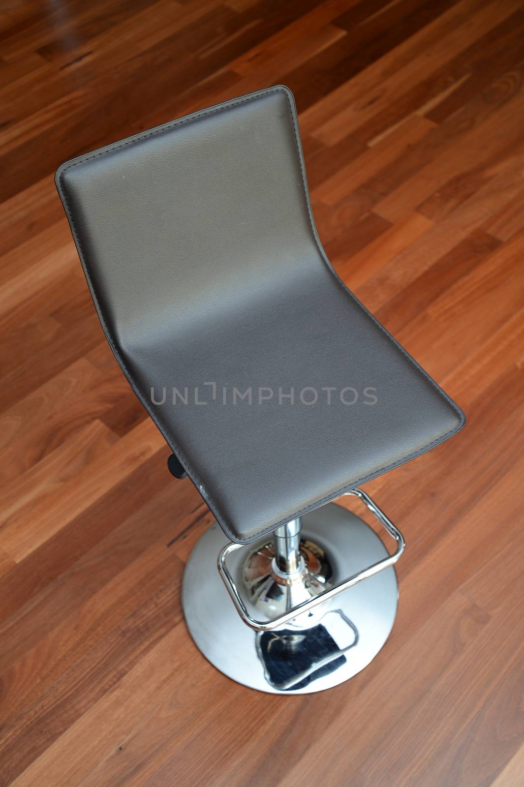 A bar stool isolated against a wooden floor