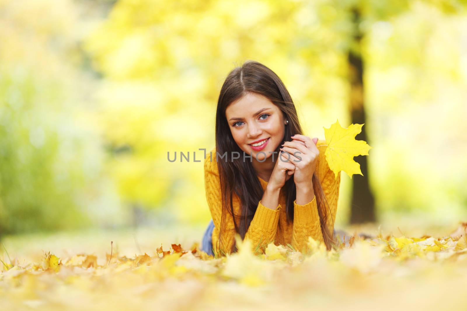 Girl laying on leafs in the autumn park