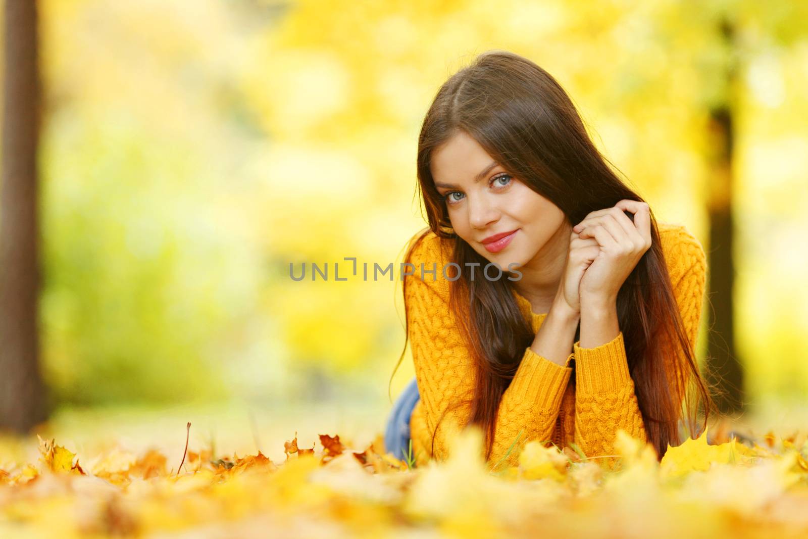 Girl laying on leafs in the autumn park