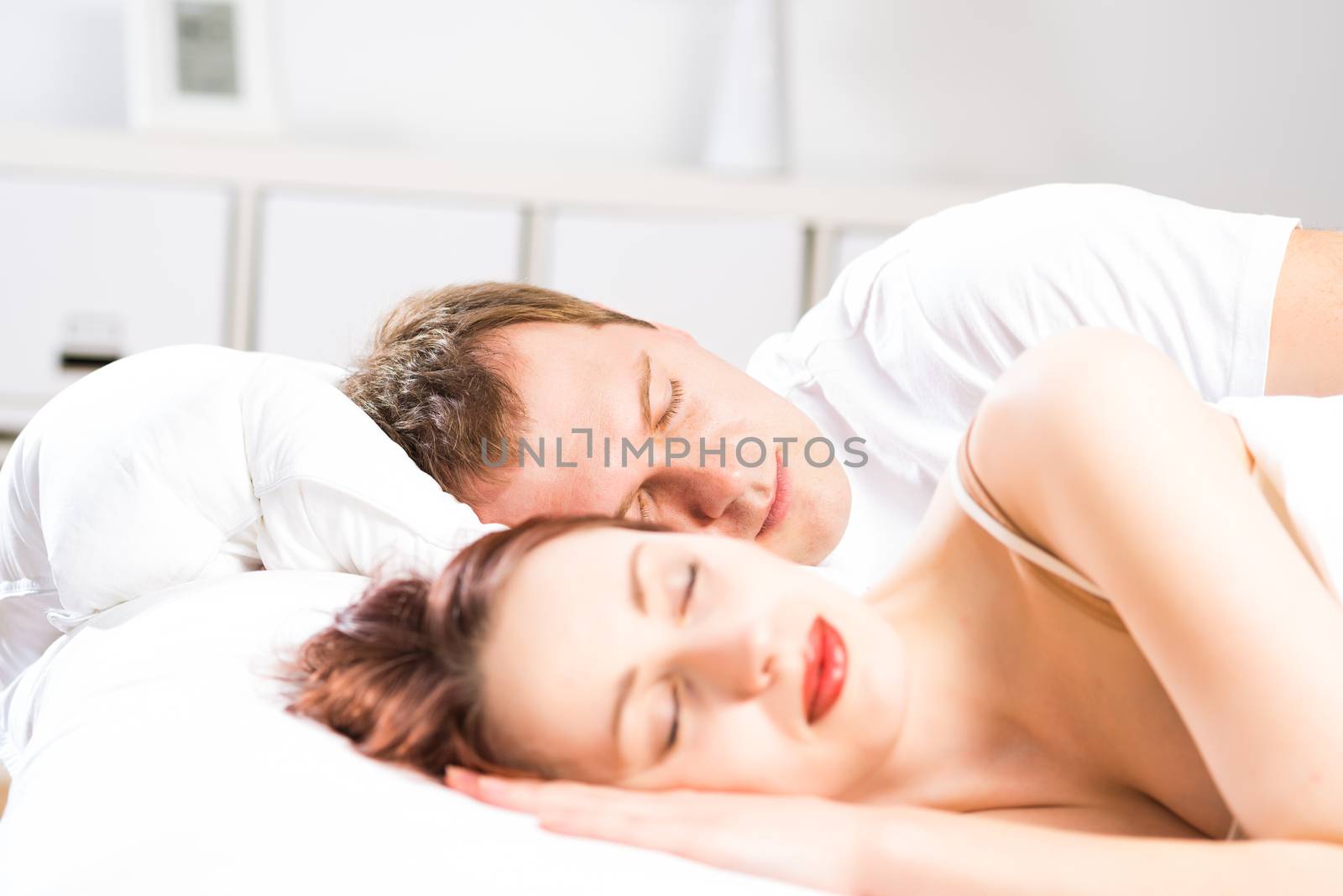 young beautiful woman sleeping on the bed with her husband