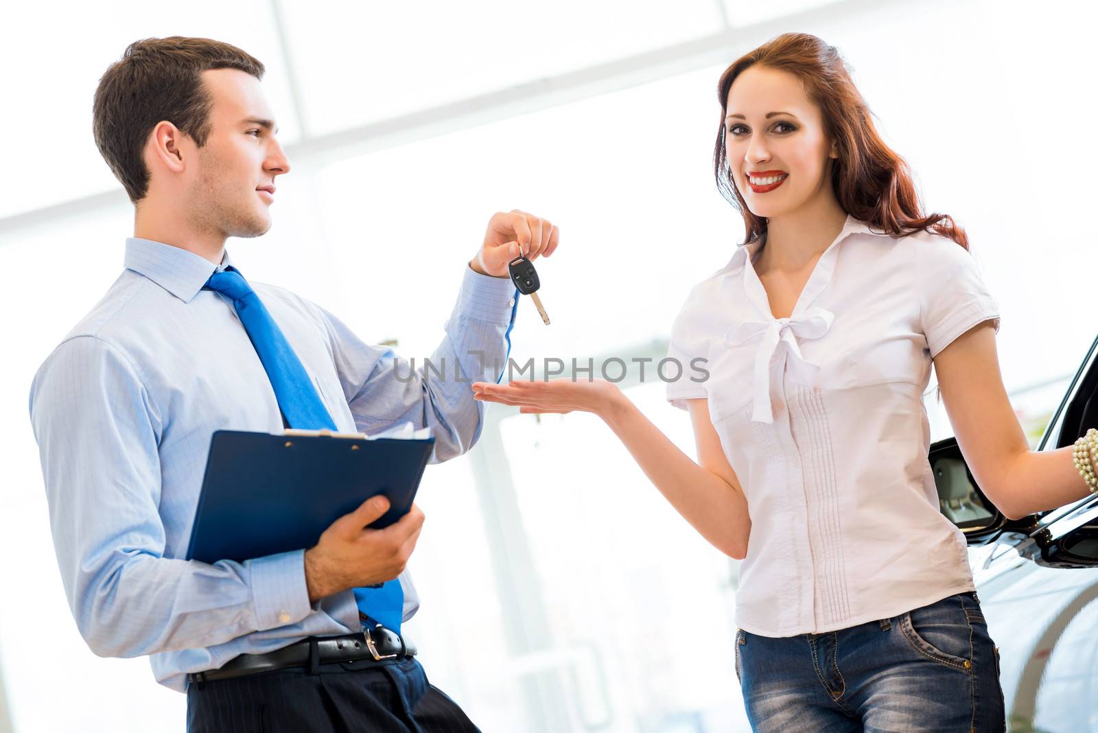 Pretty woman receives the keys to a new car from a sales manager