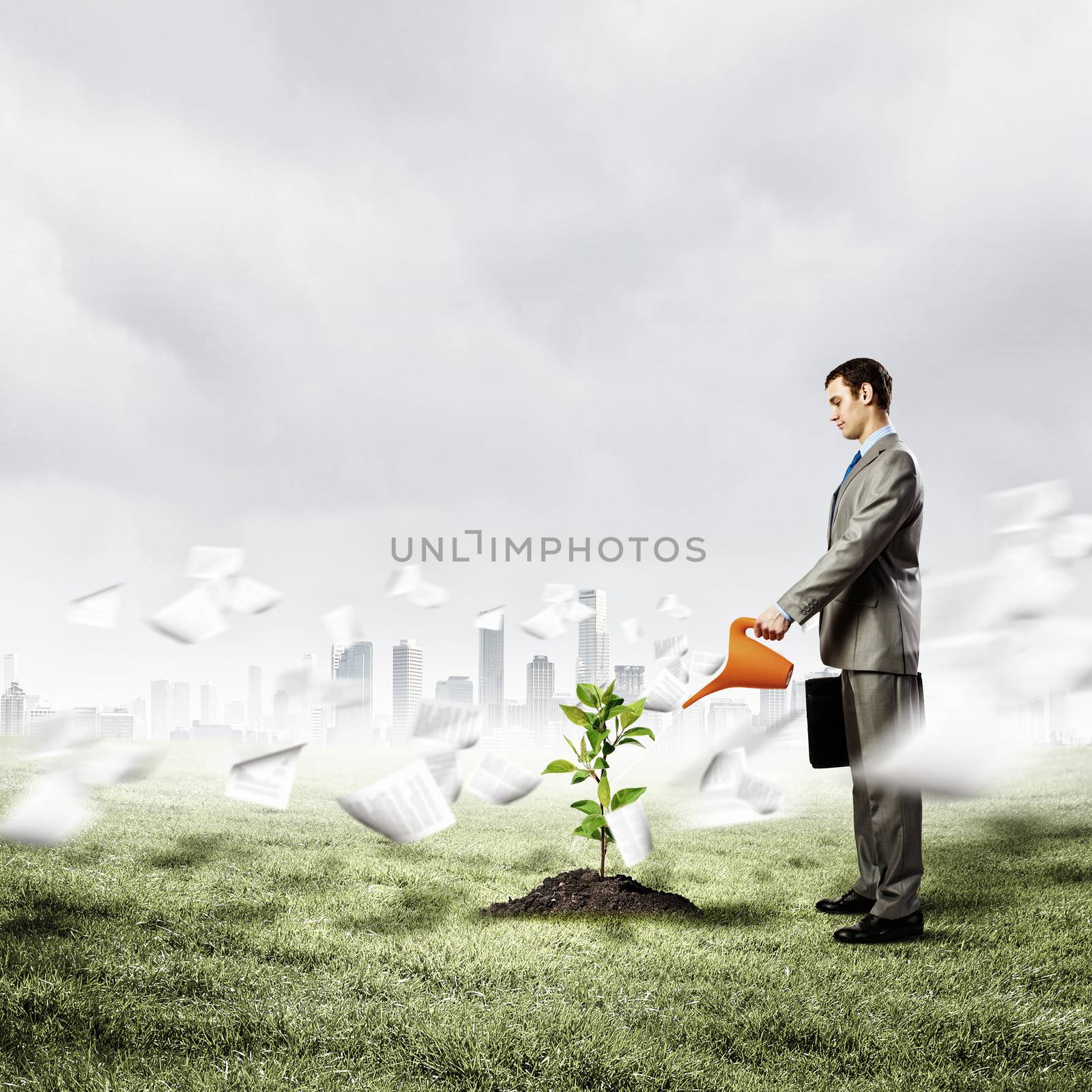 Image of businessman watering sprout with can