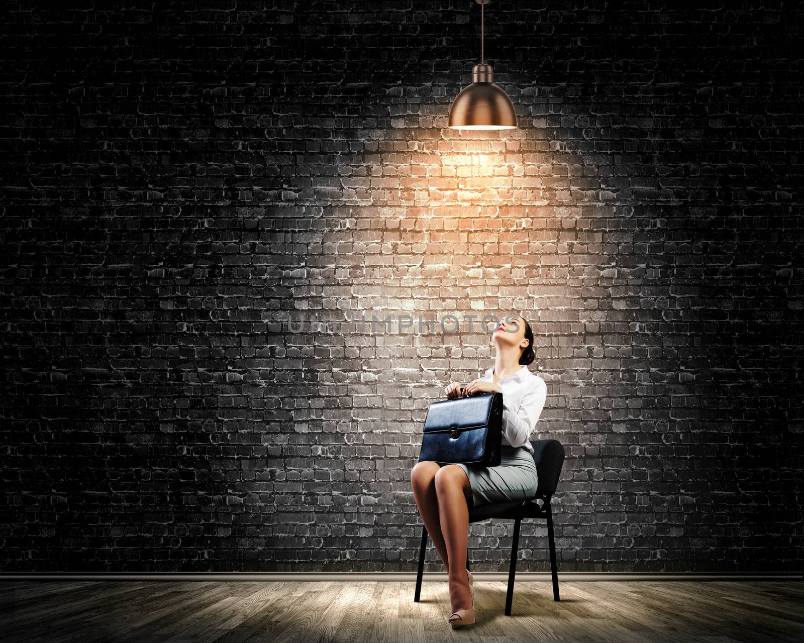 Image of young businesswoman sitting on chair under spot of light