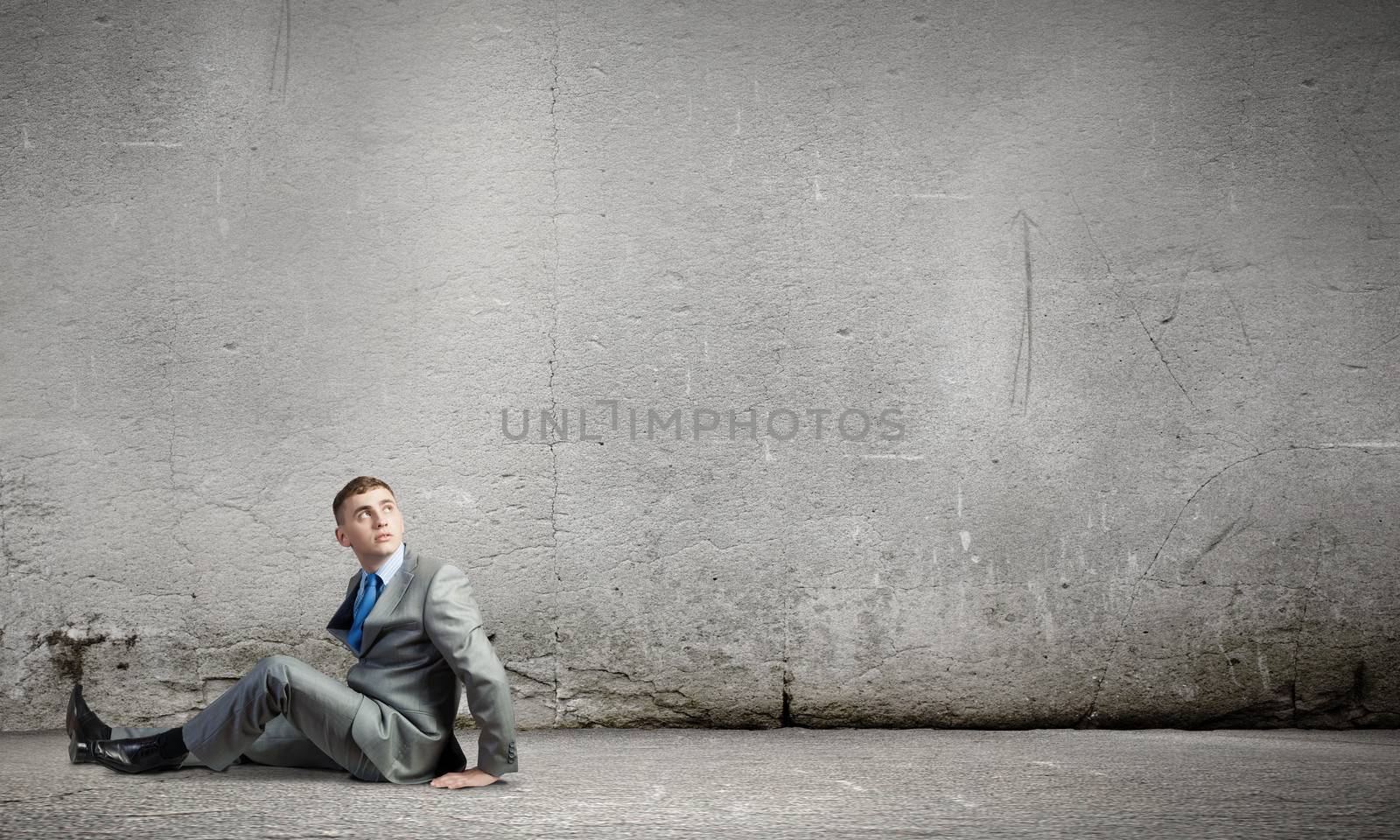 Image of young businessman sitting lonely on floor