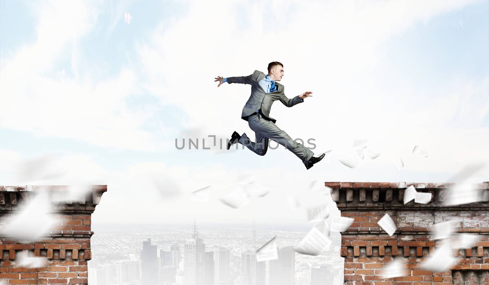 Image of young businessman jumping over gap in bridge