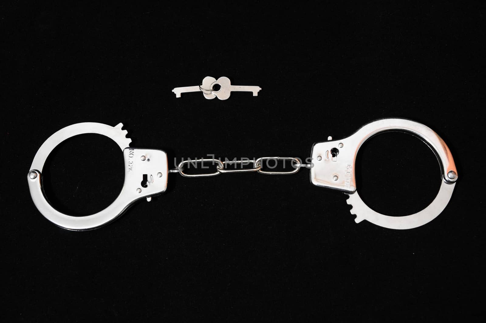 One Pair of Handcuffs on a Black Background